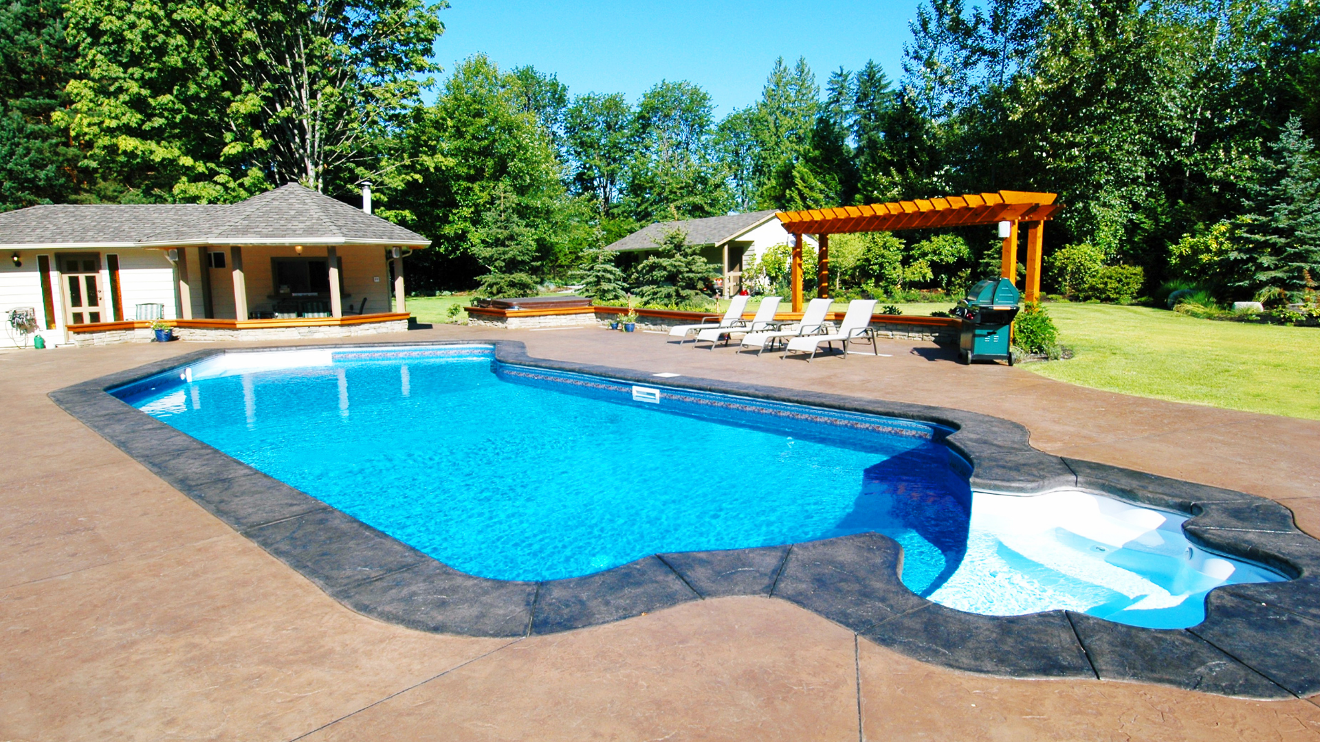 Picture of a stamped concrete pool.  The concrete is coloured with a coloured border around the pool.