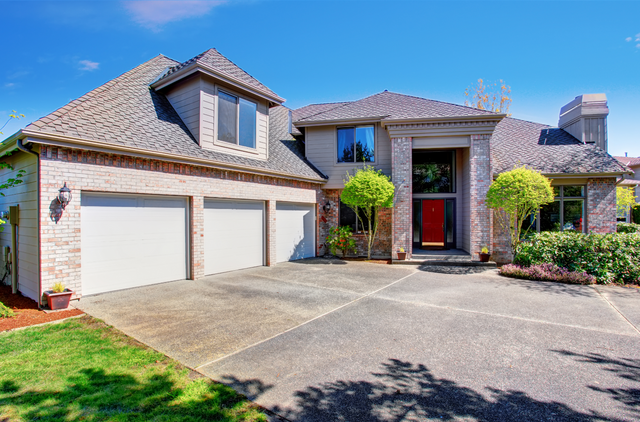 Picture of a concrete driveway.  The driveway is in front of a triple car garage.