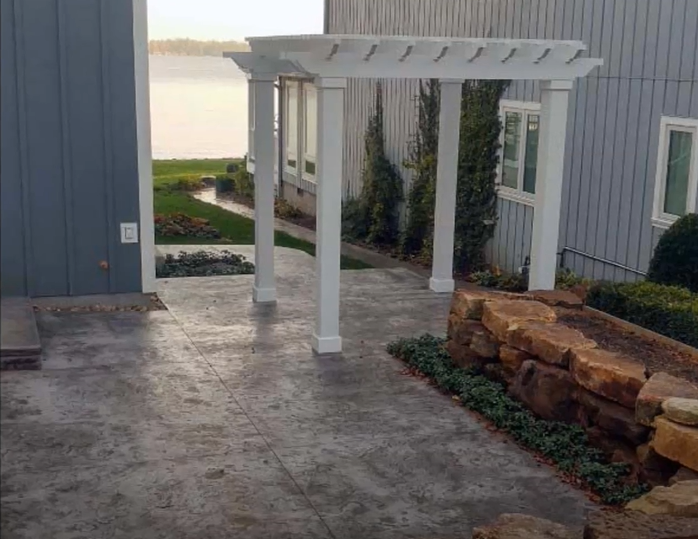 Picture of a stamped concrete patio area outside of a house.  There is also a concrete walkway leading to the back of the house.