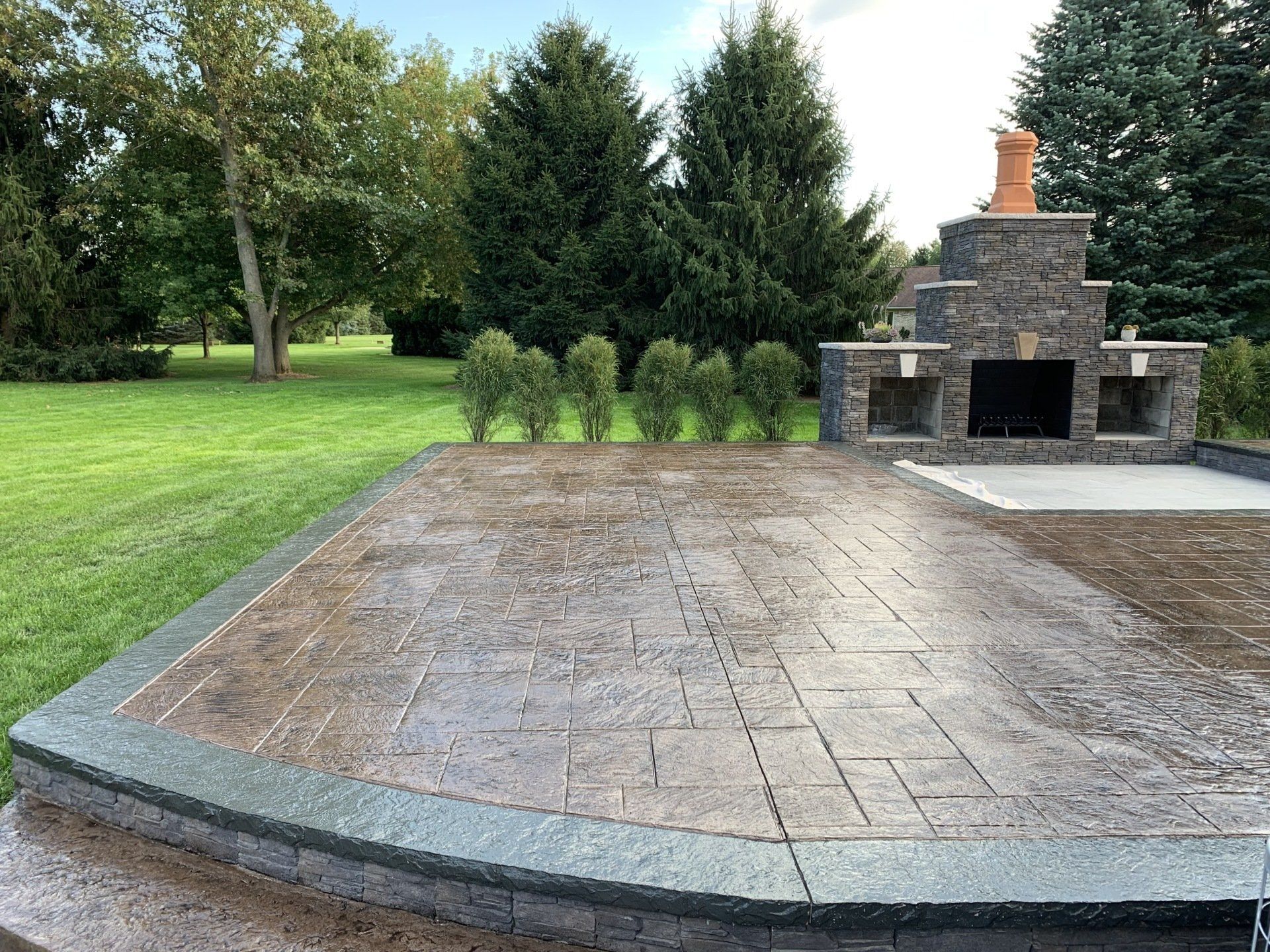 This is a picture of a new stamped concrete patio in front of an outdoor fireplace.