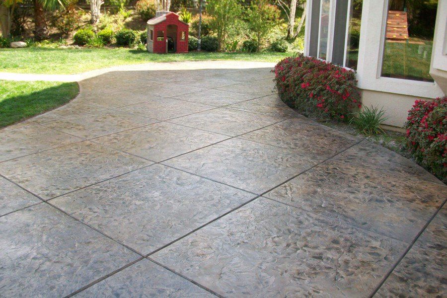 This is a picture of a concrete patio and walkway outside of a house.