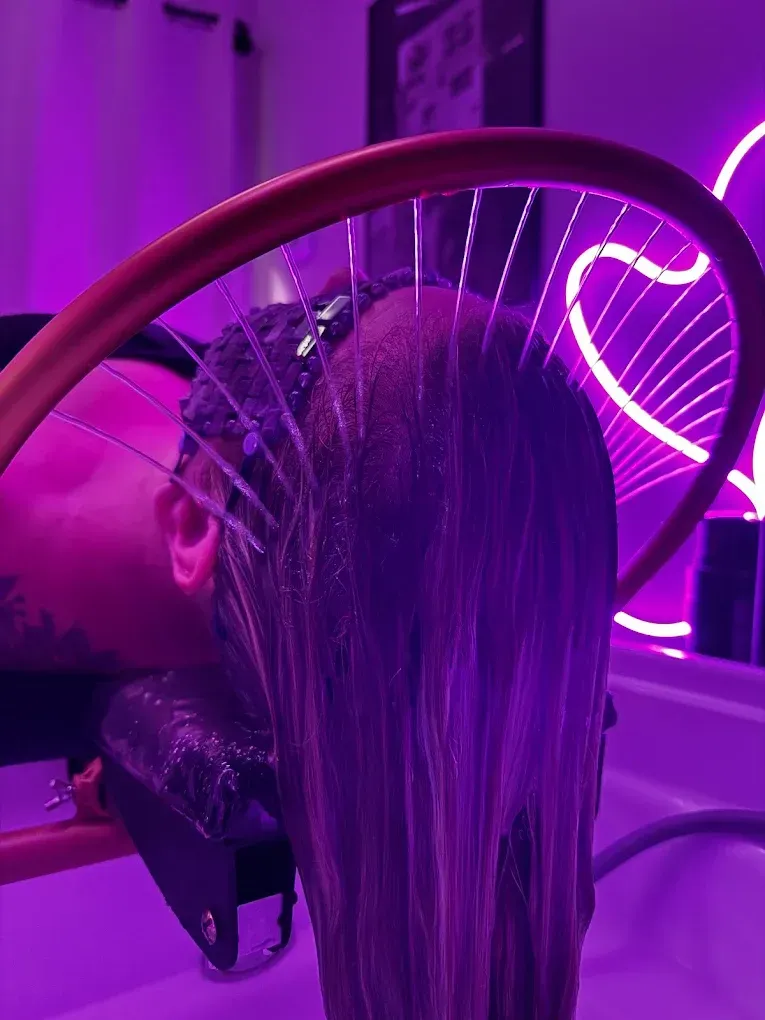 Person getting hair washed at a salon with purple lighting.