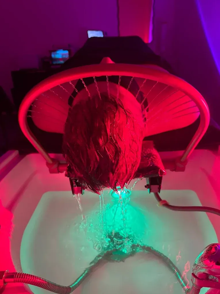 Person having hair washed in a salon with red and green lights.