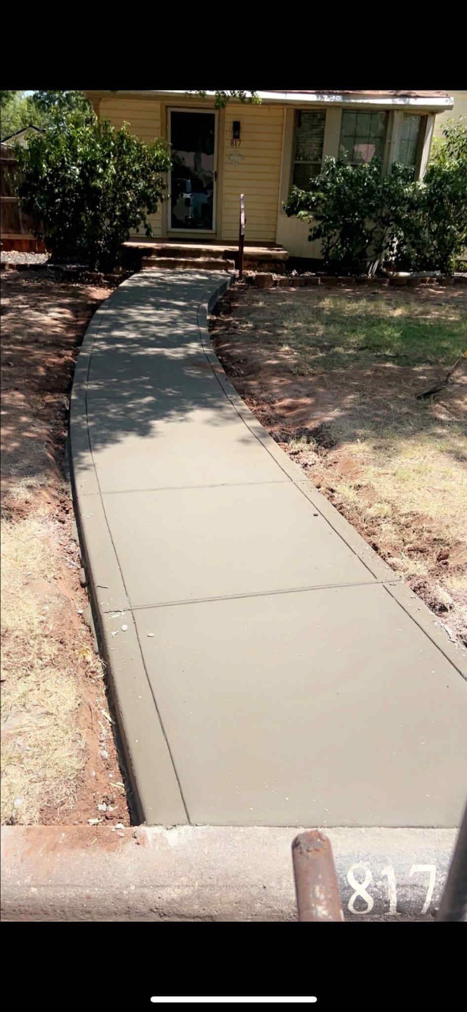 Freshly poured concrete walkway leading to a house.