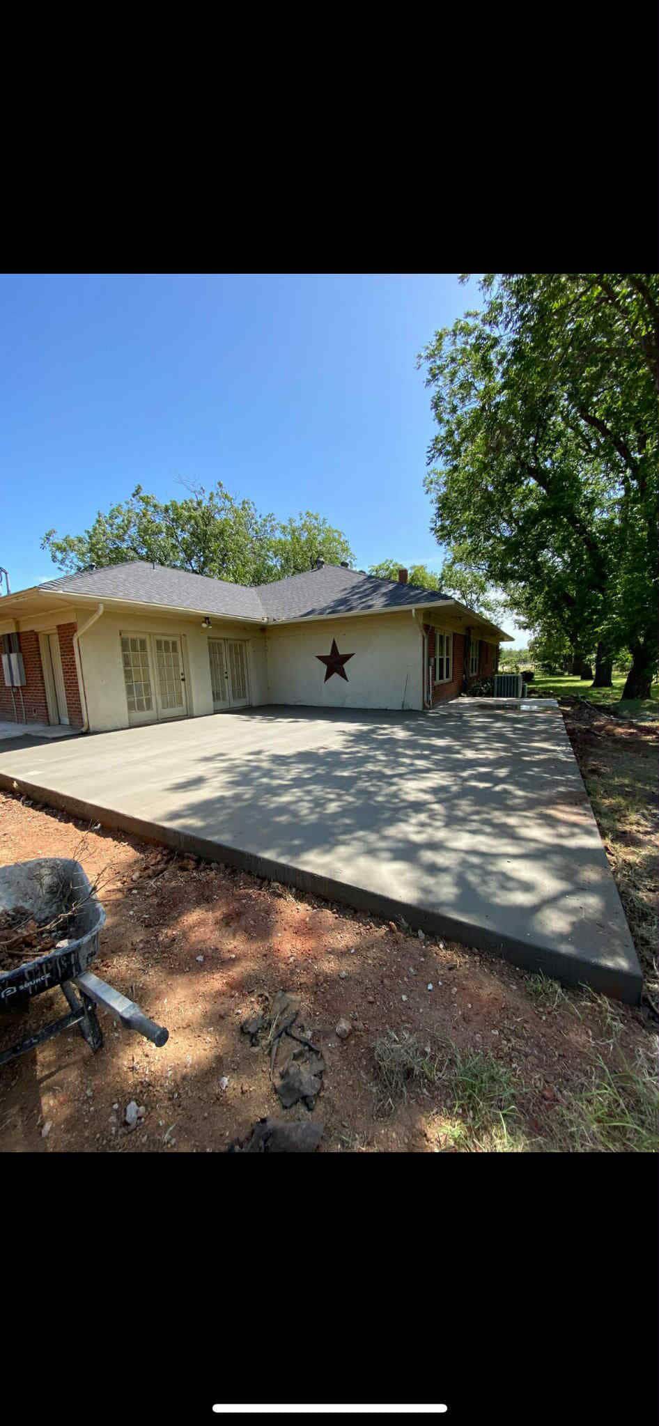 A concrete patio extends from a light-colored house with a star on the side; blue sky overhead.