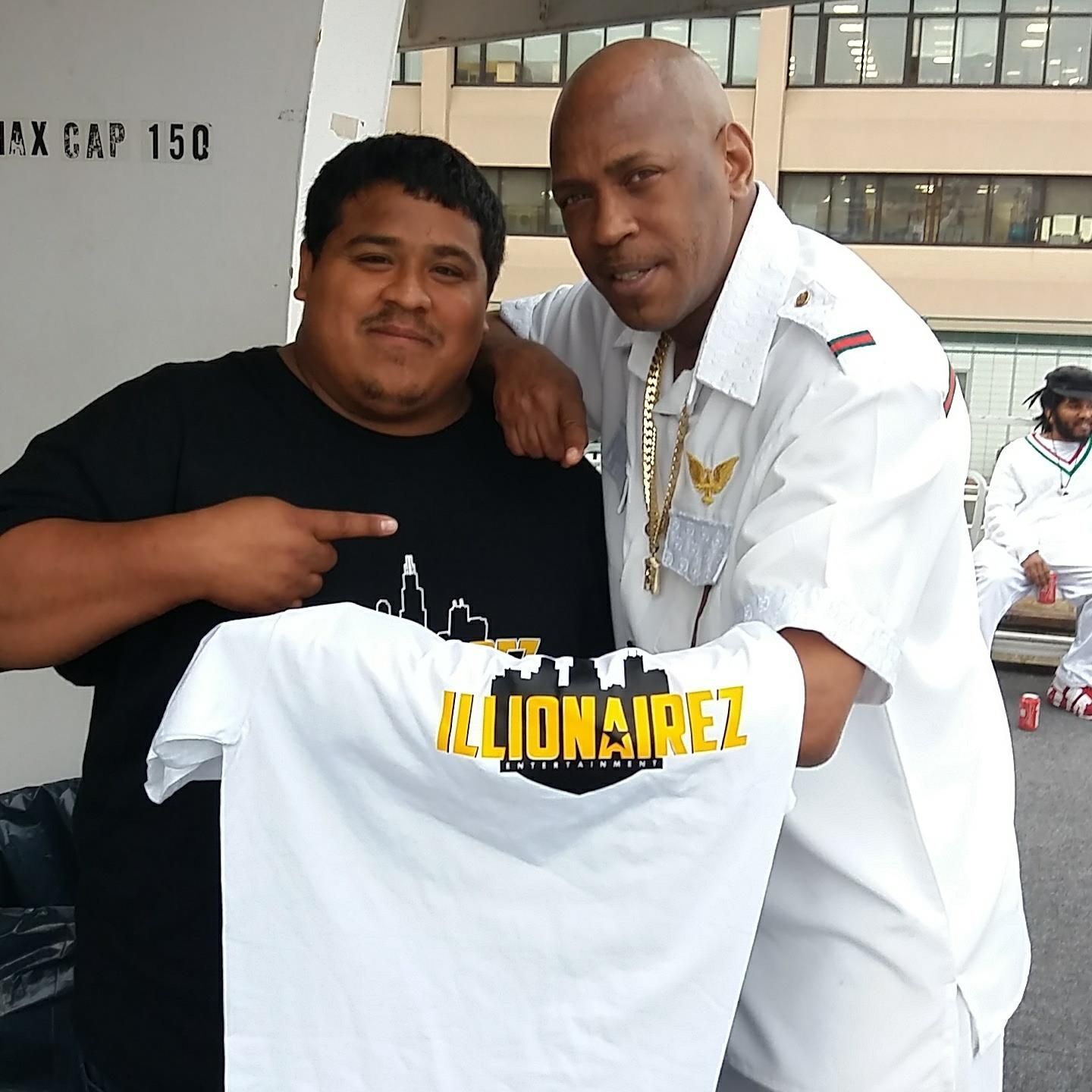 A man holding a billionaire t-shirt next to another man