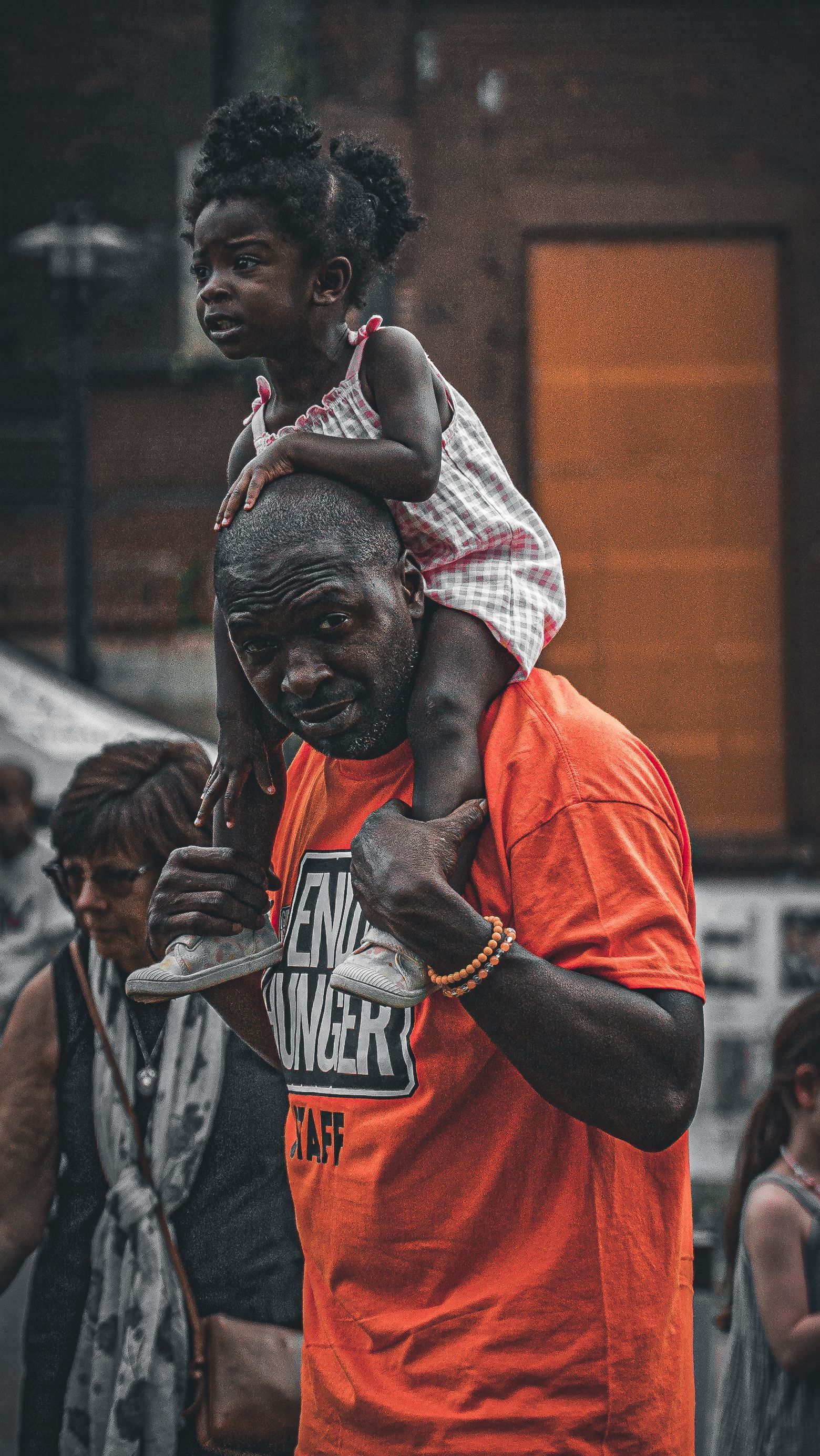 A man is carrying a little girl on his shoulders.