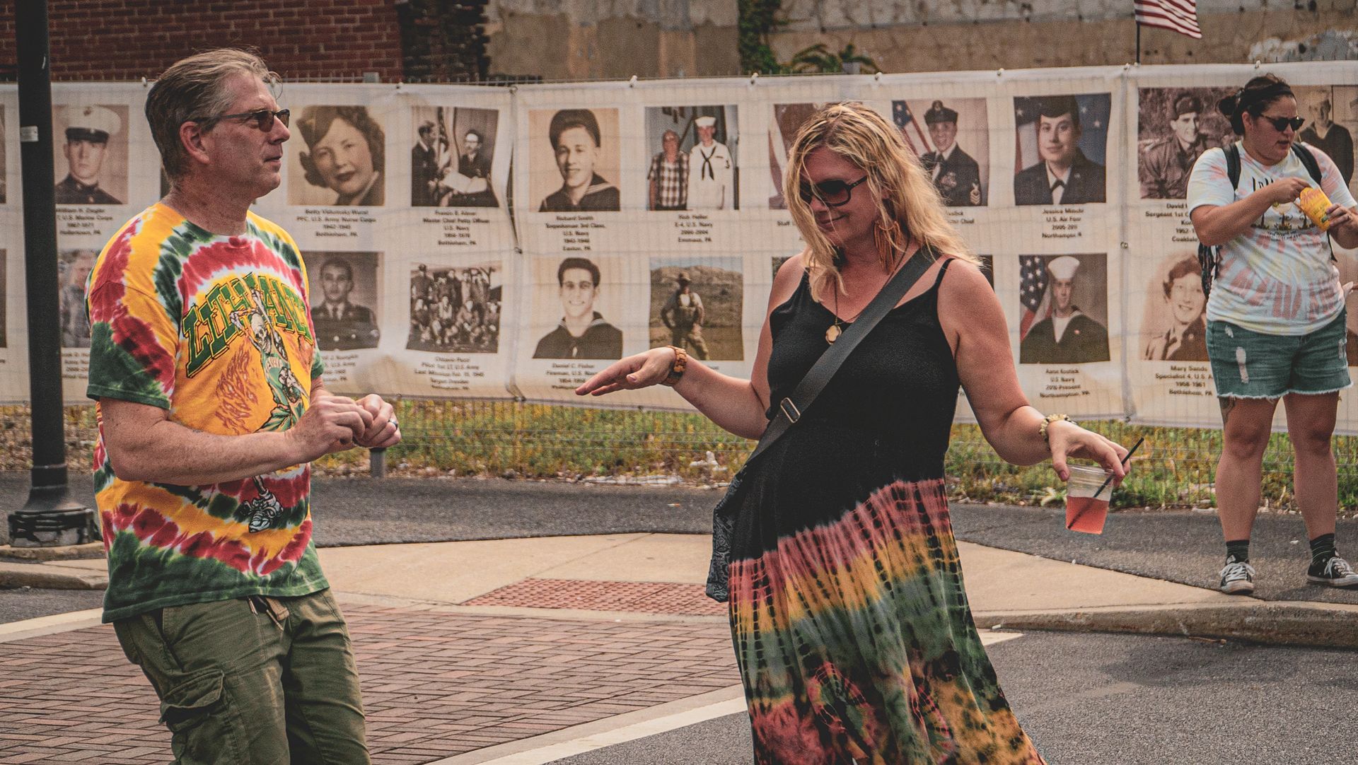 A man and a woman are standing in front of a wall with pictures of people.