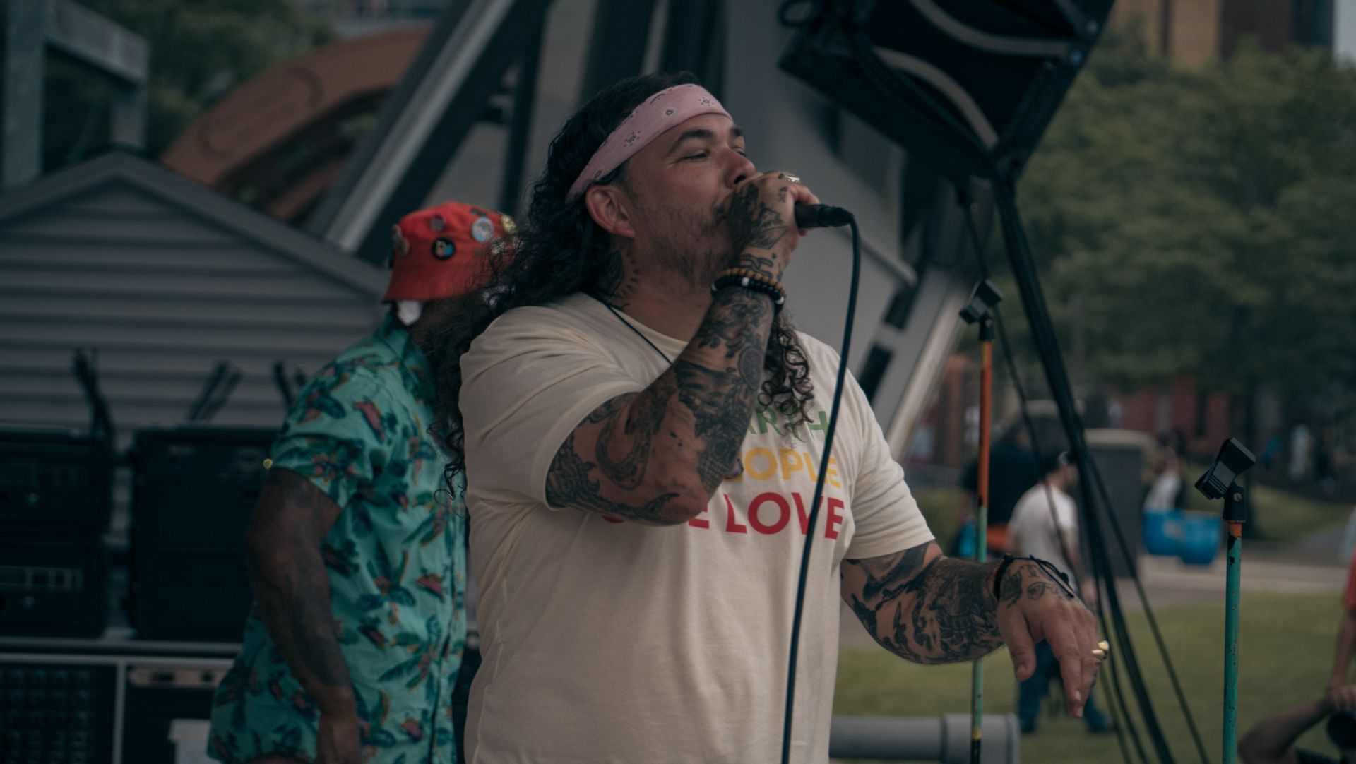 A man with long hair is singing into a microphone.