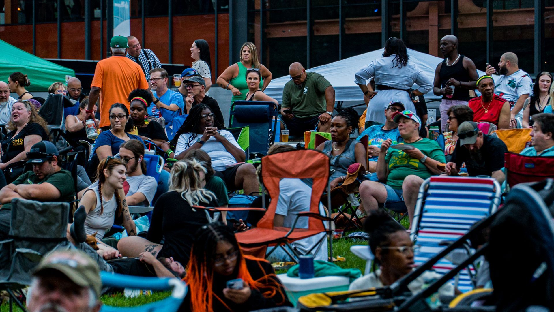 A large group of people are sitting in chairs in a park.