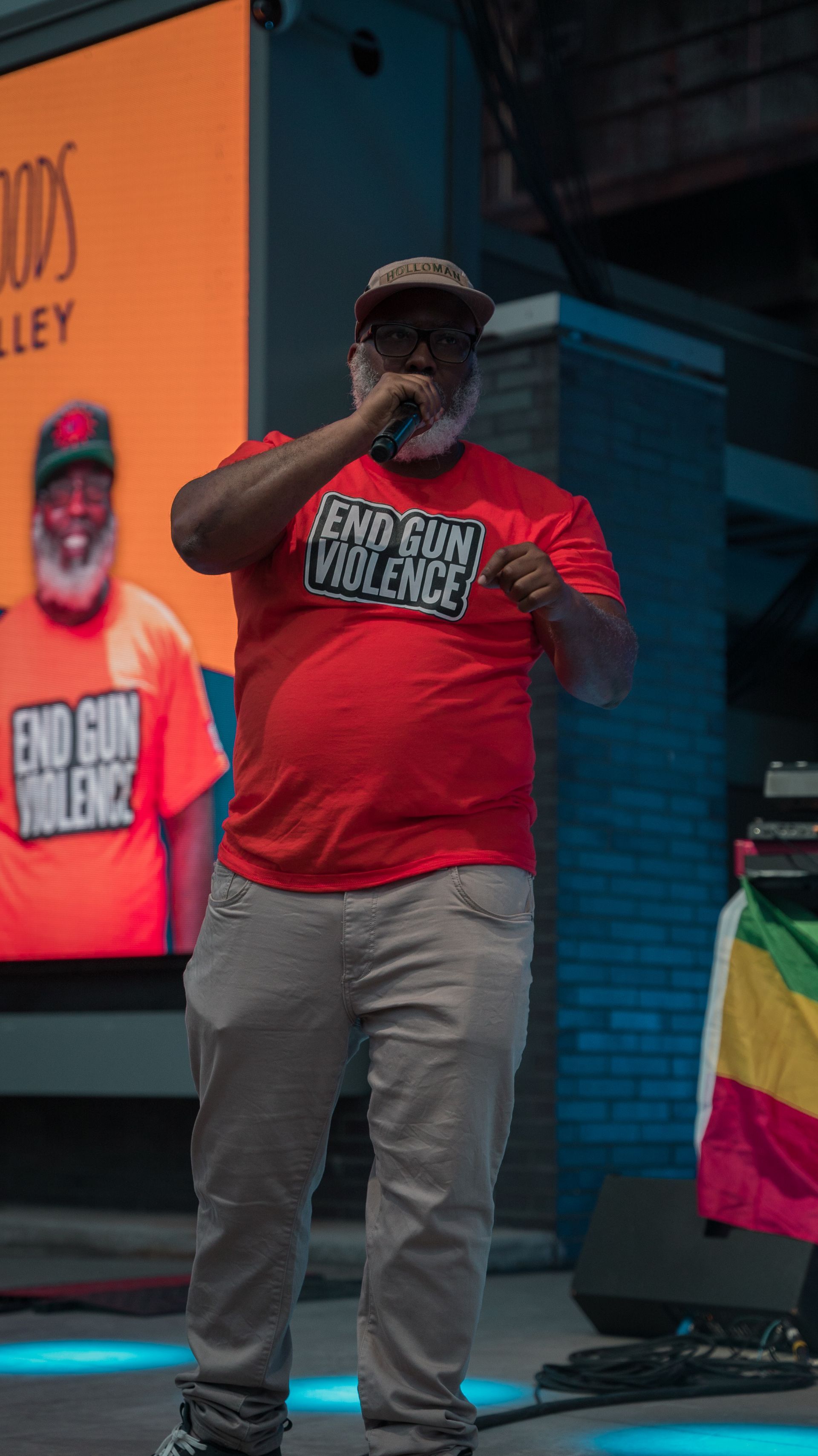 A man in a red shirt is standing on a stage holding a microphone.
