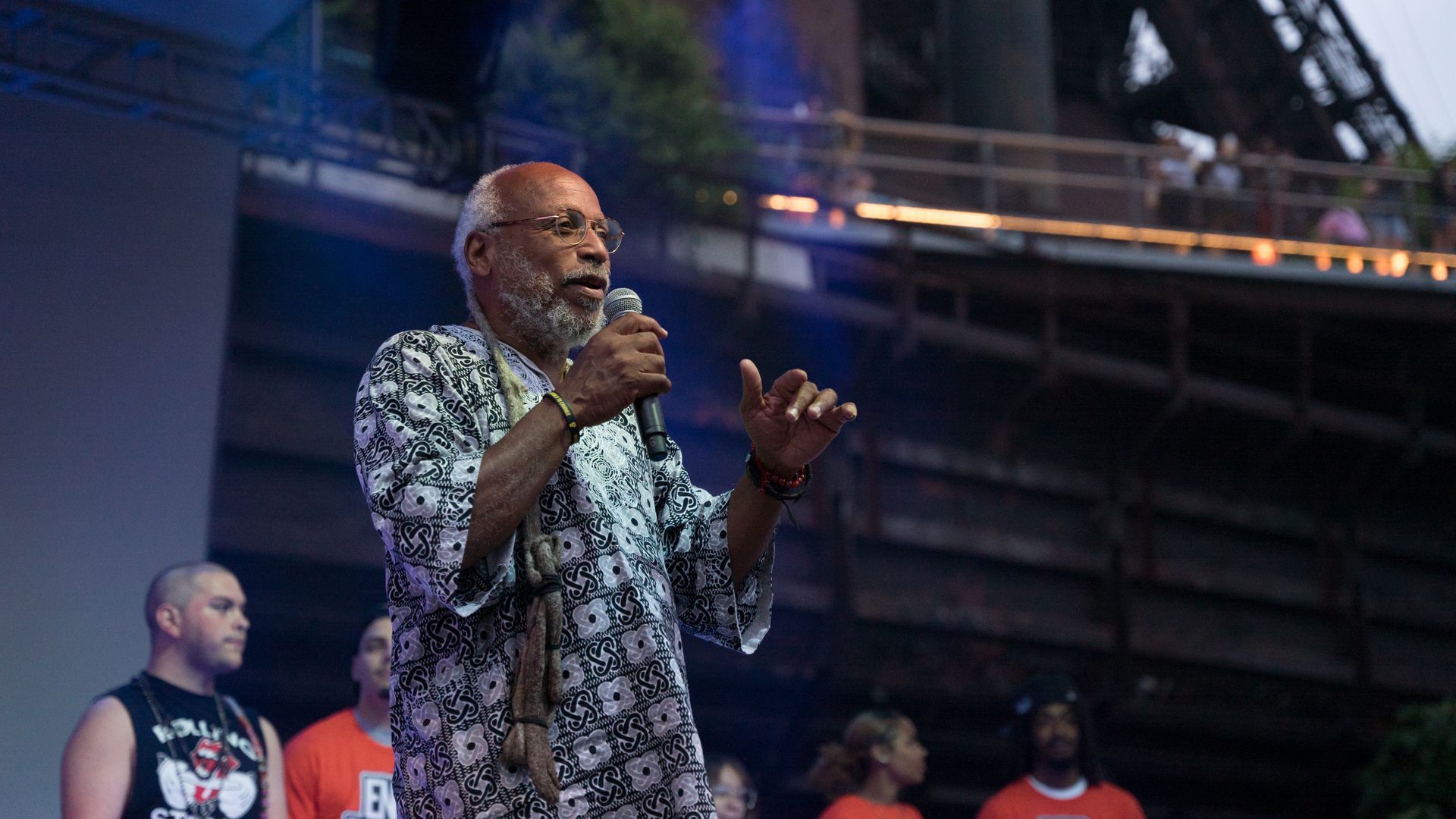 A man with a beard is standing on a stage holding a microphone.