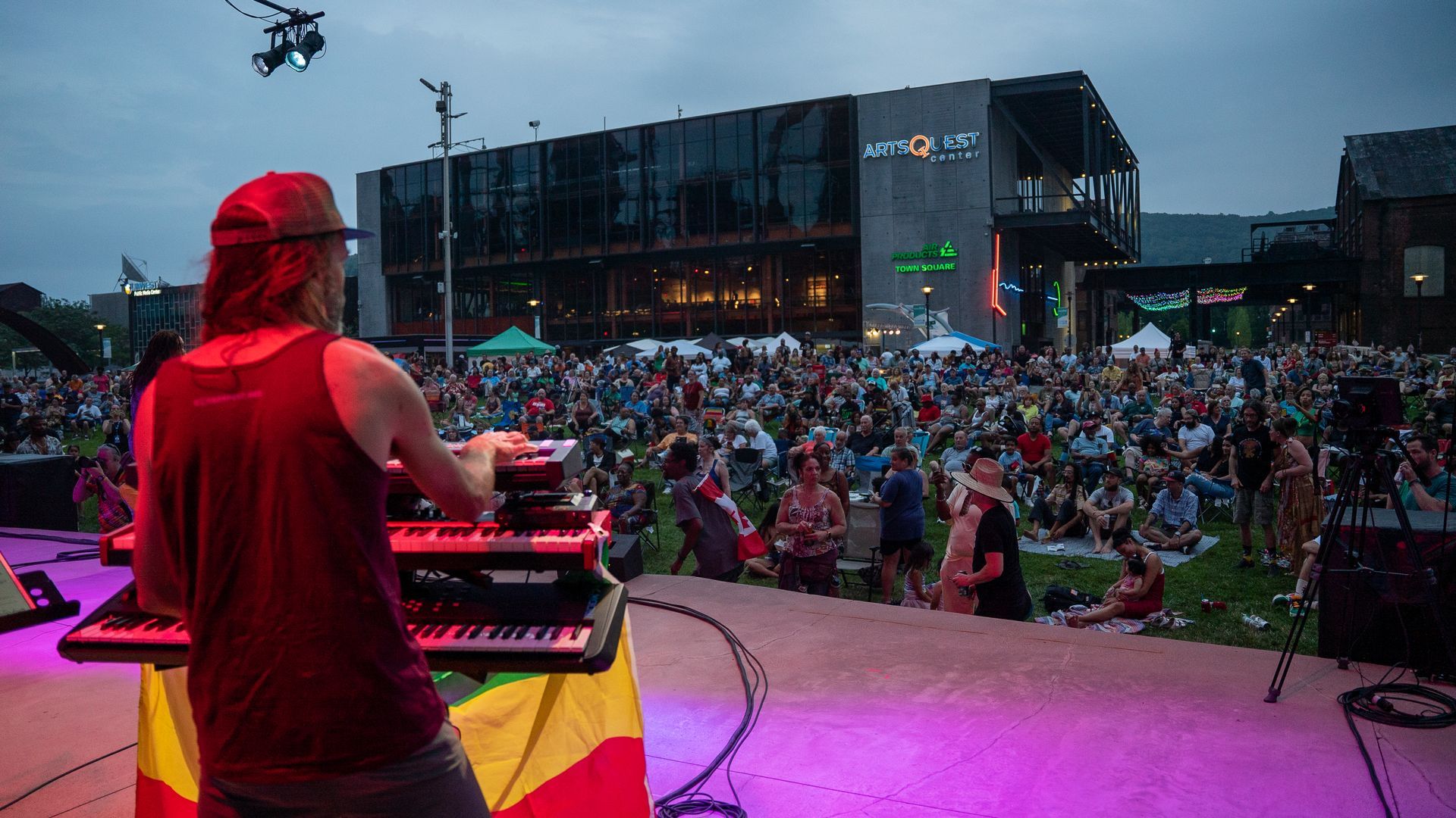 A man is playing a keyboard on a stage in front of a crowd.