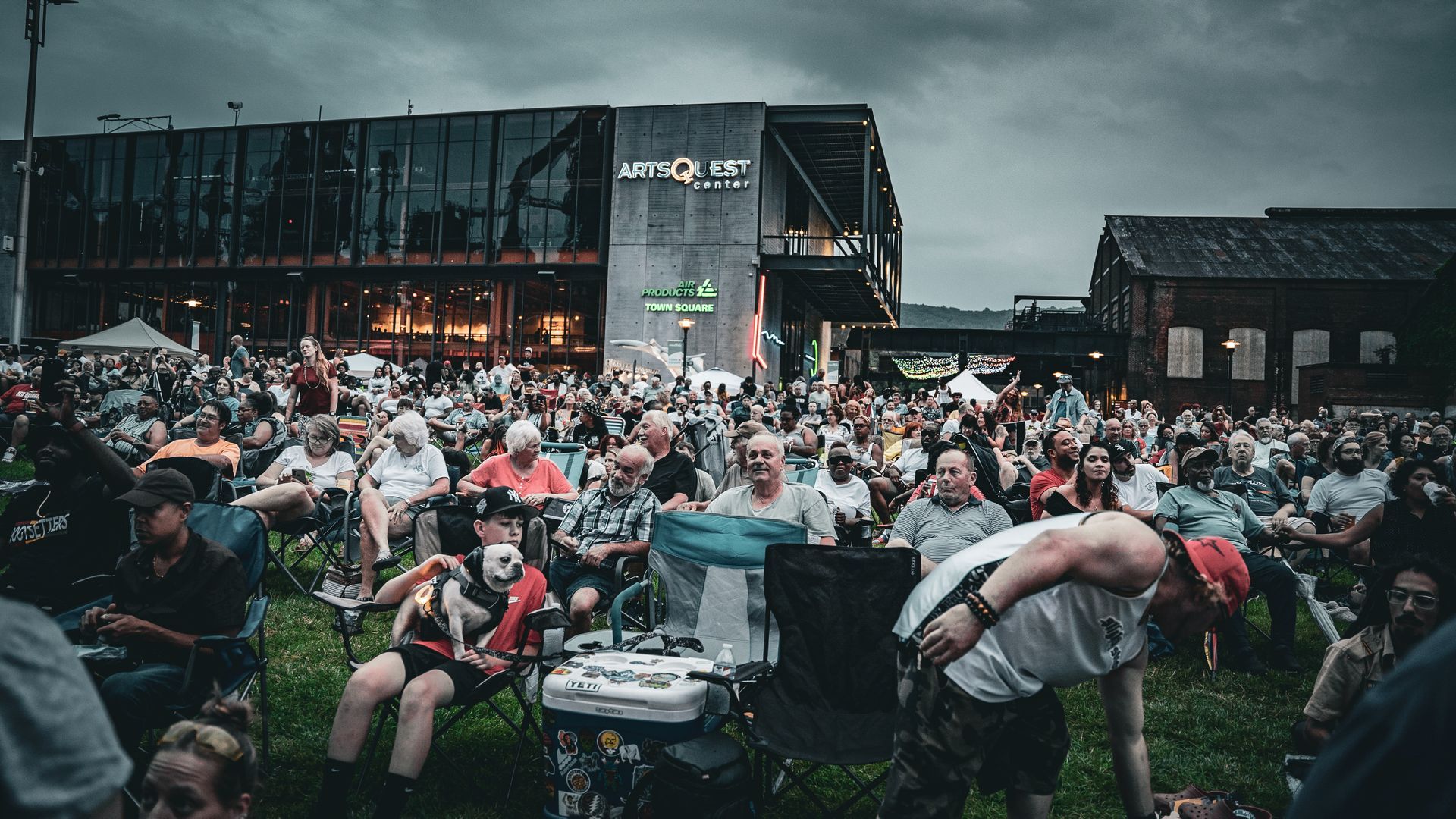 A crowd of people are sitting in chairs in front of a building.