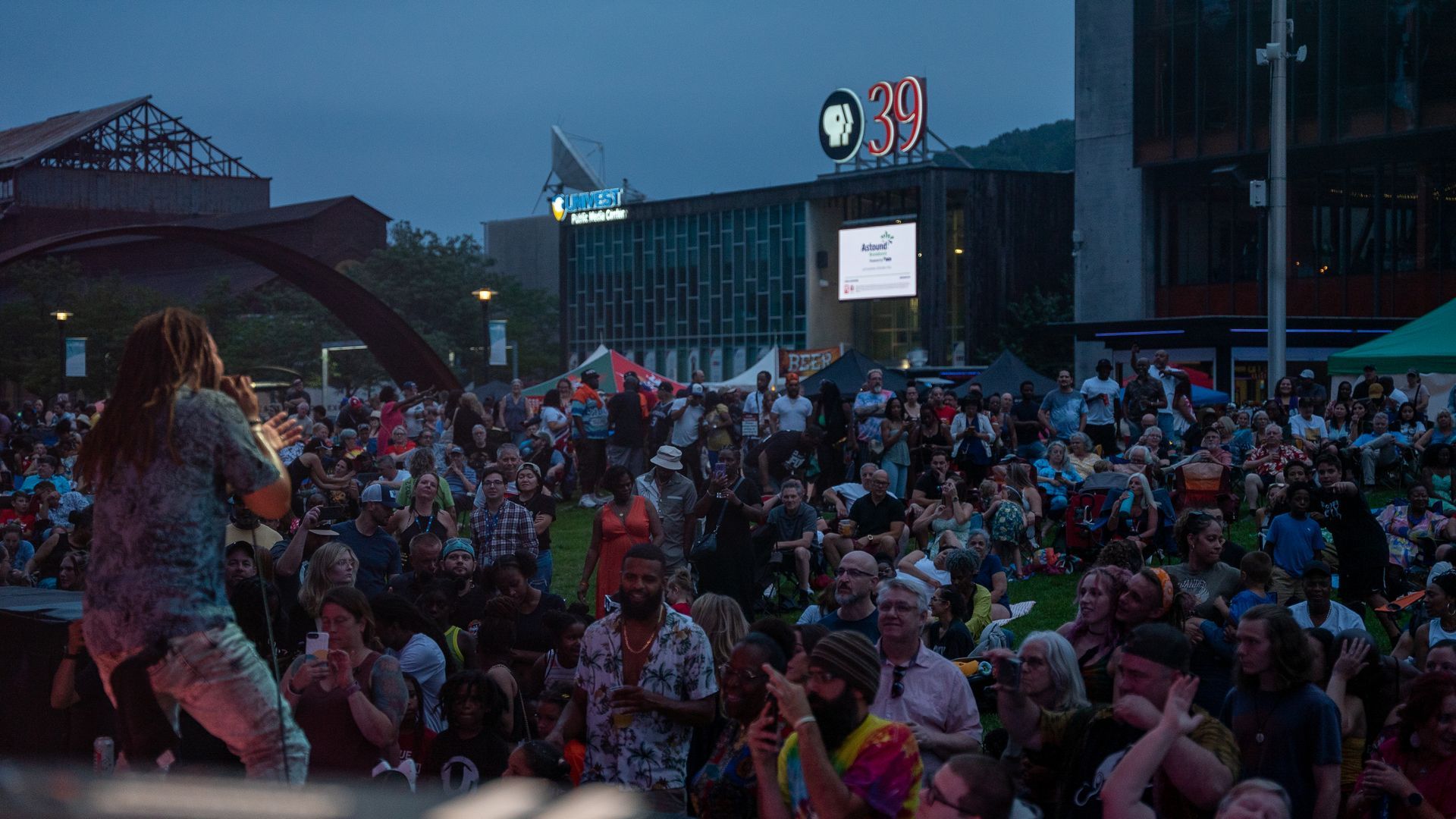 A man is singing into a microphone in front of a crowd of people at a concert.
