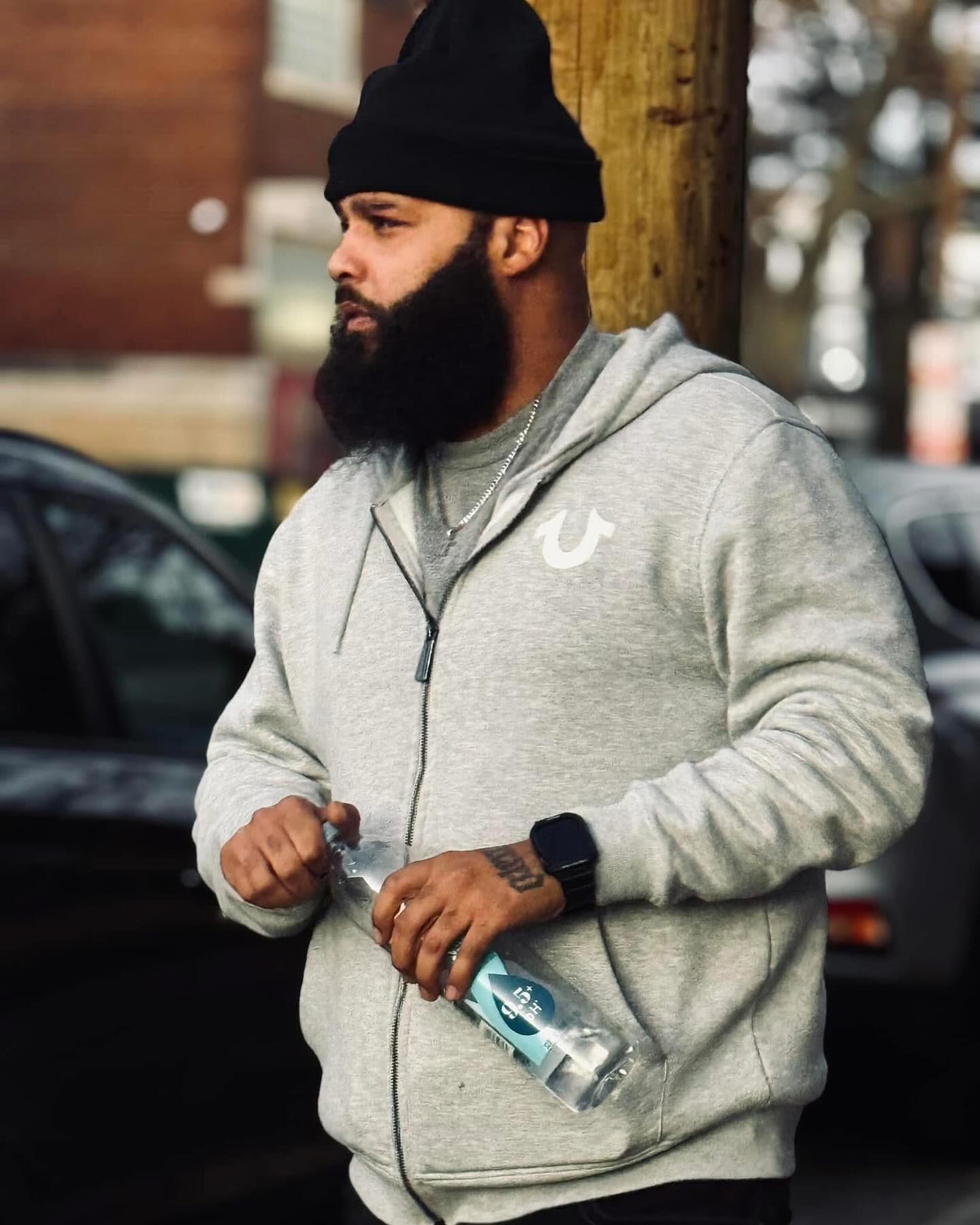 A man with a beard wearing a true religion hoodie