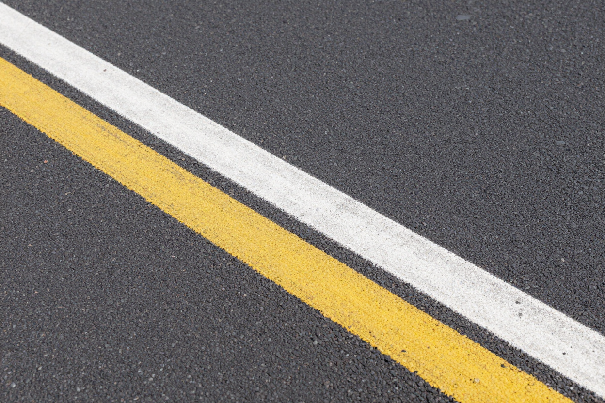 Diagonal white and yellow road lines on dark asphalt