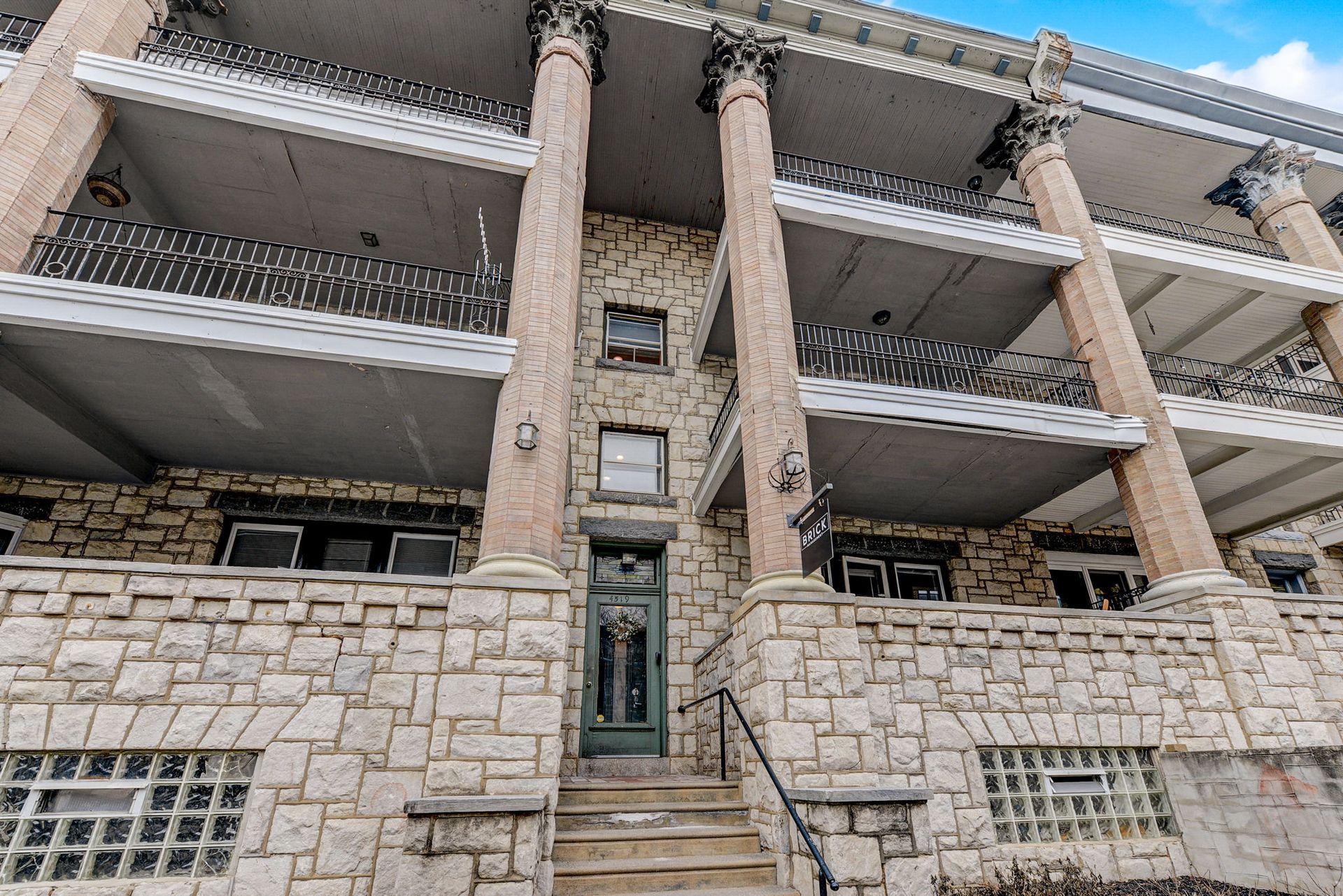 Photo of a large building with multiple balconies, and the steps to the entrance in the middle of the photo