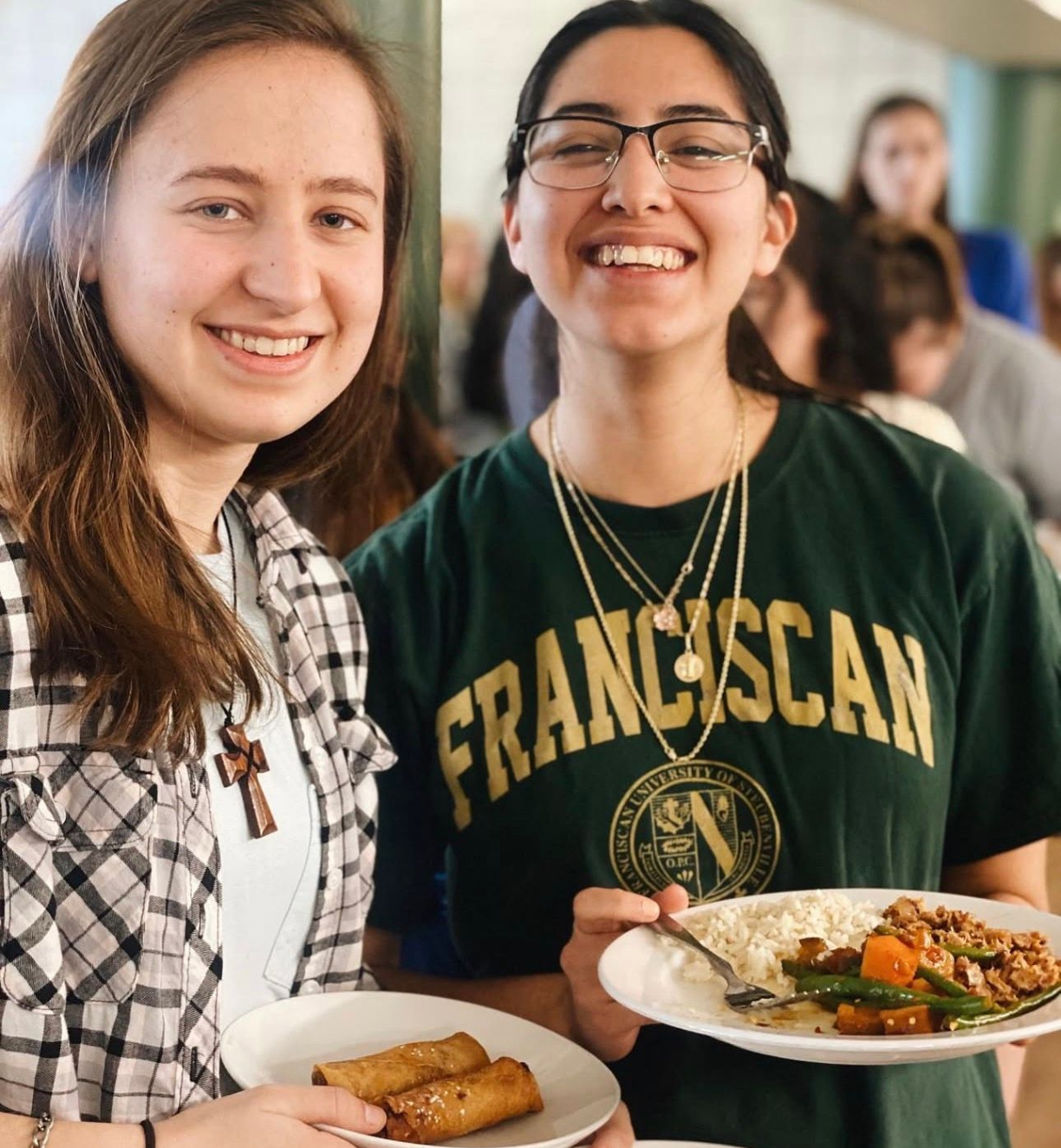 Two students holding plates of food. 