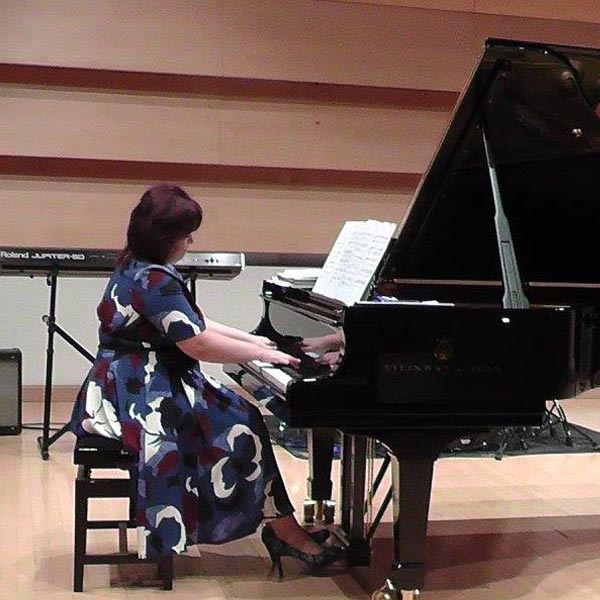Olga Morozova sat at a grand piano wearing a blue and white dress