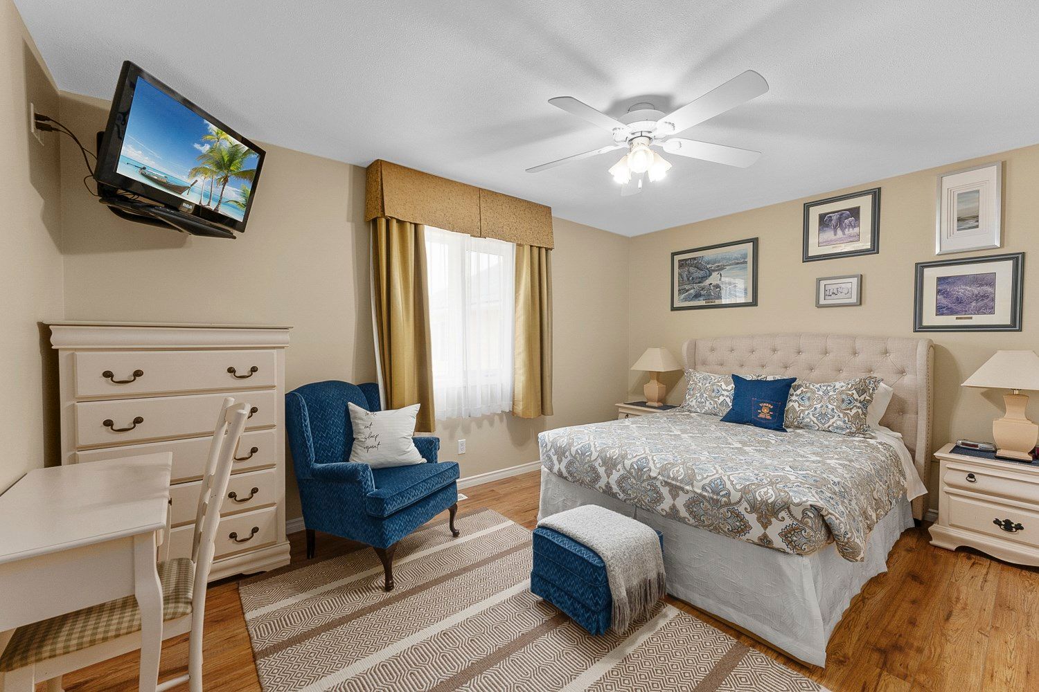 A bedroom with a queen size bed , chair , dresser and television. Lakeshore Inn Bed & Breakfast