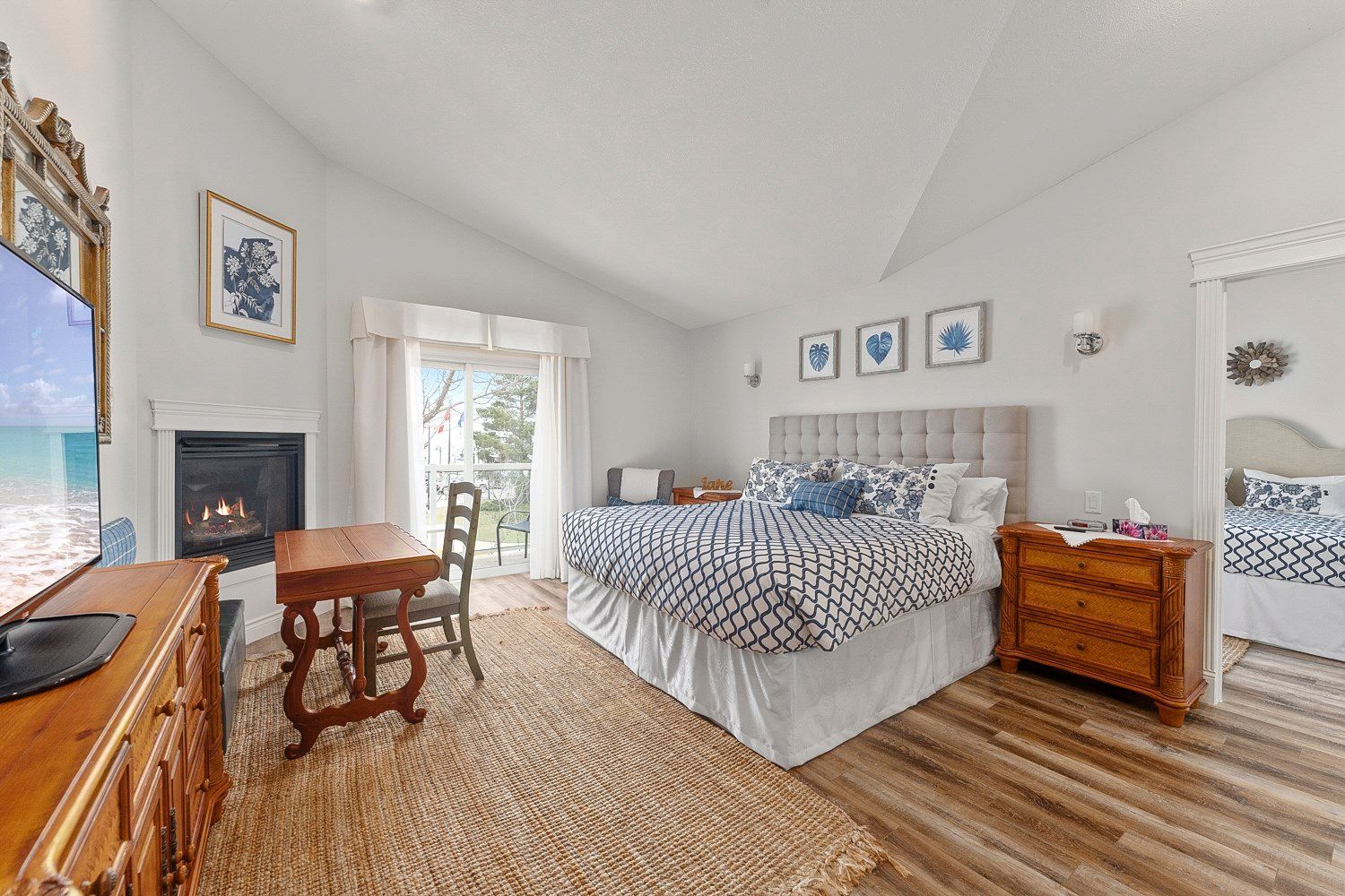 A bedroom with a king size bed , fireplace , desk, television, balcony, and lake view. Lakeshore Inn Bed & Breakfast