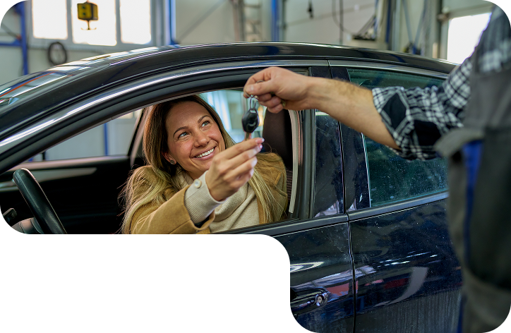 A woman is sitting in a car getting a car key from a mechanic. | D & B Bear Service