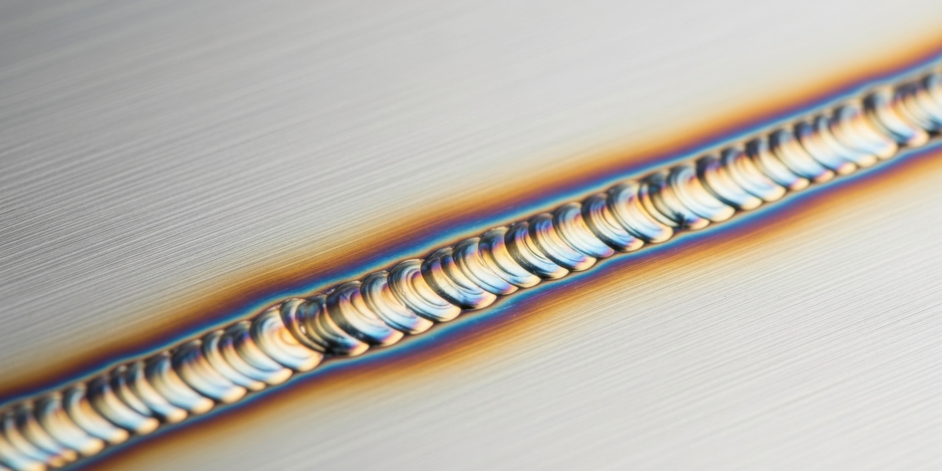 A man in an orange jumpsuit is standing in a factory writing on a clipboard.