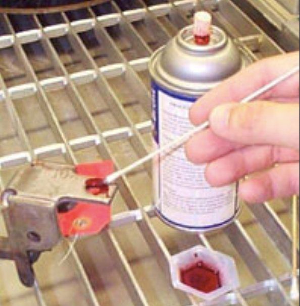 A person is cleaning a metal object with a spray can