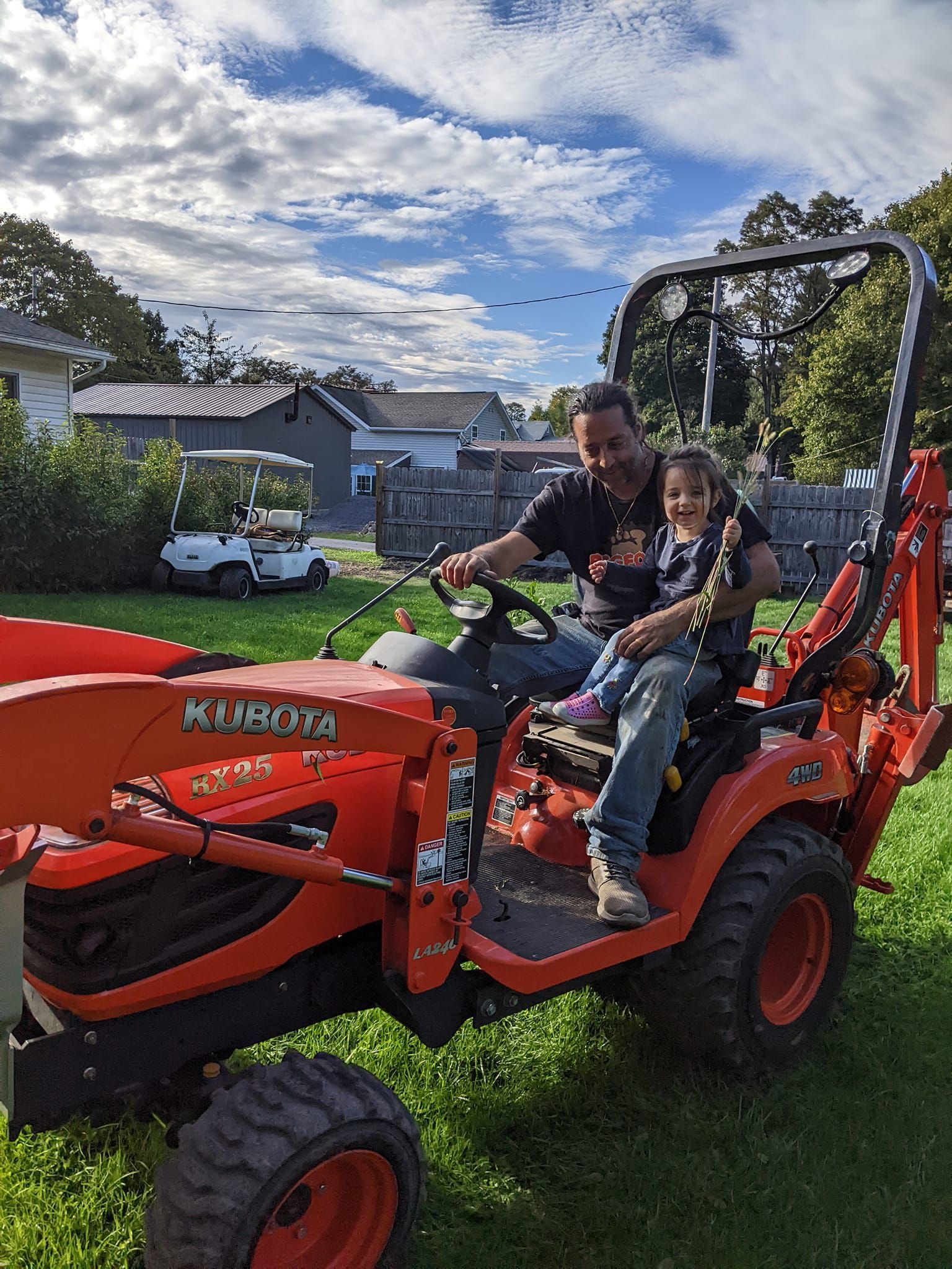 A man and a little girl are sitting on a tractor.