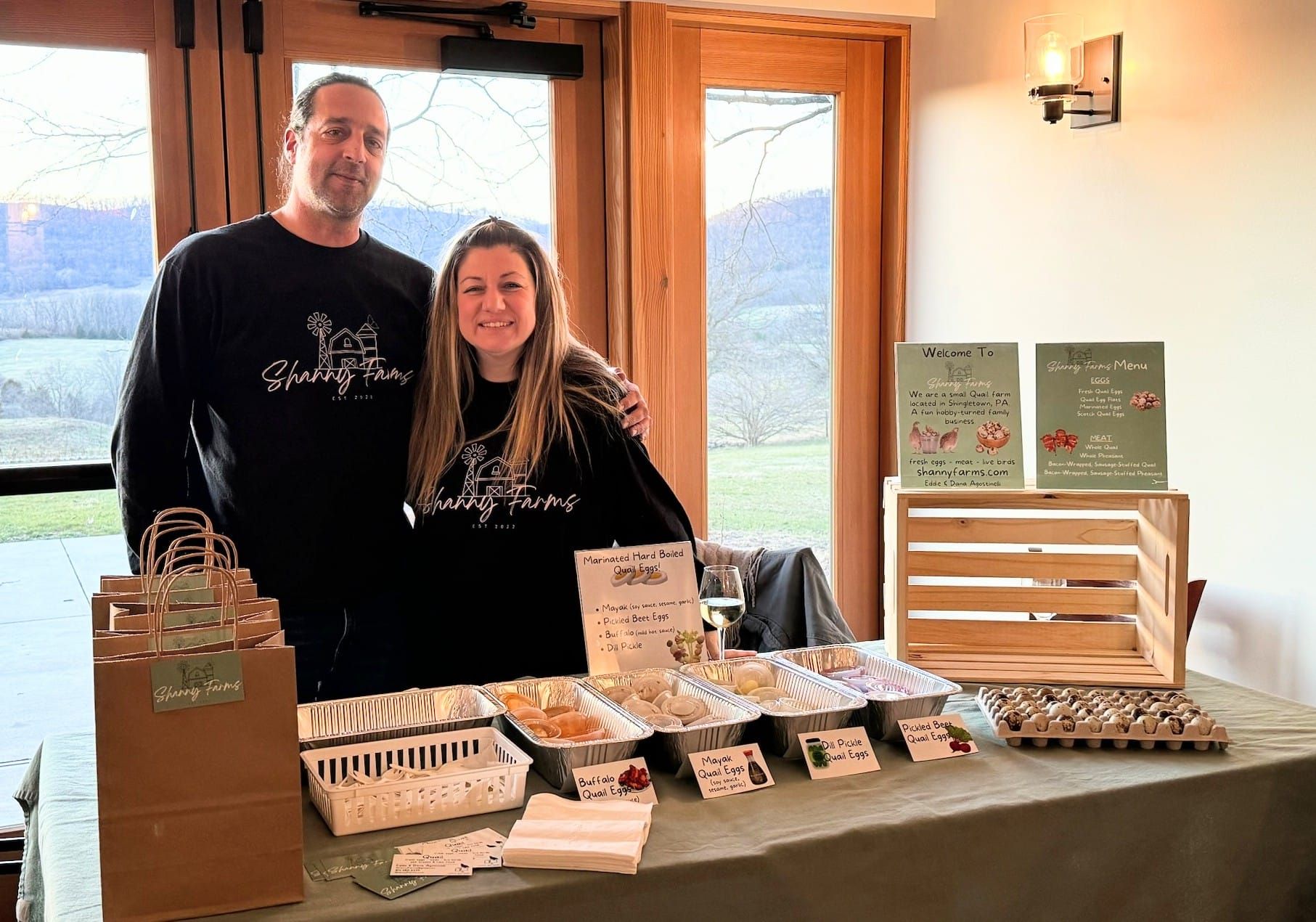 A man and a woman are standing in front of a table with food on it.