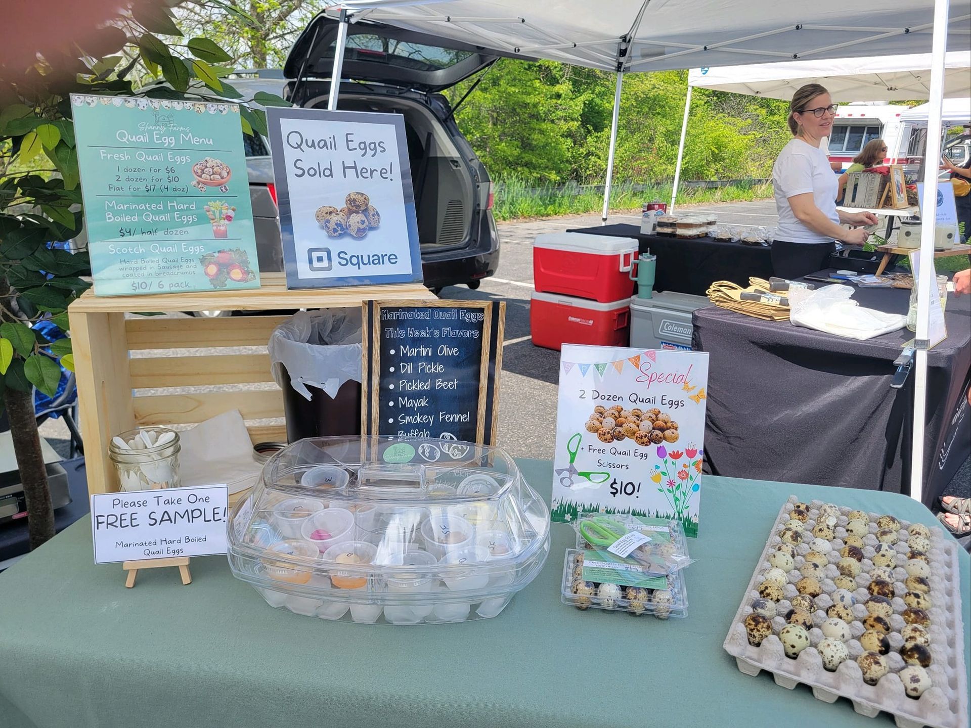 A woman is standing behind a table selling quail eggs.