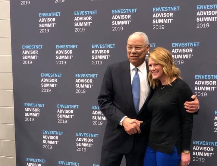 A man and a woman are posing for a picture in front of a wall that says investnet advisor summit 2019.