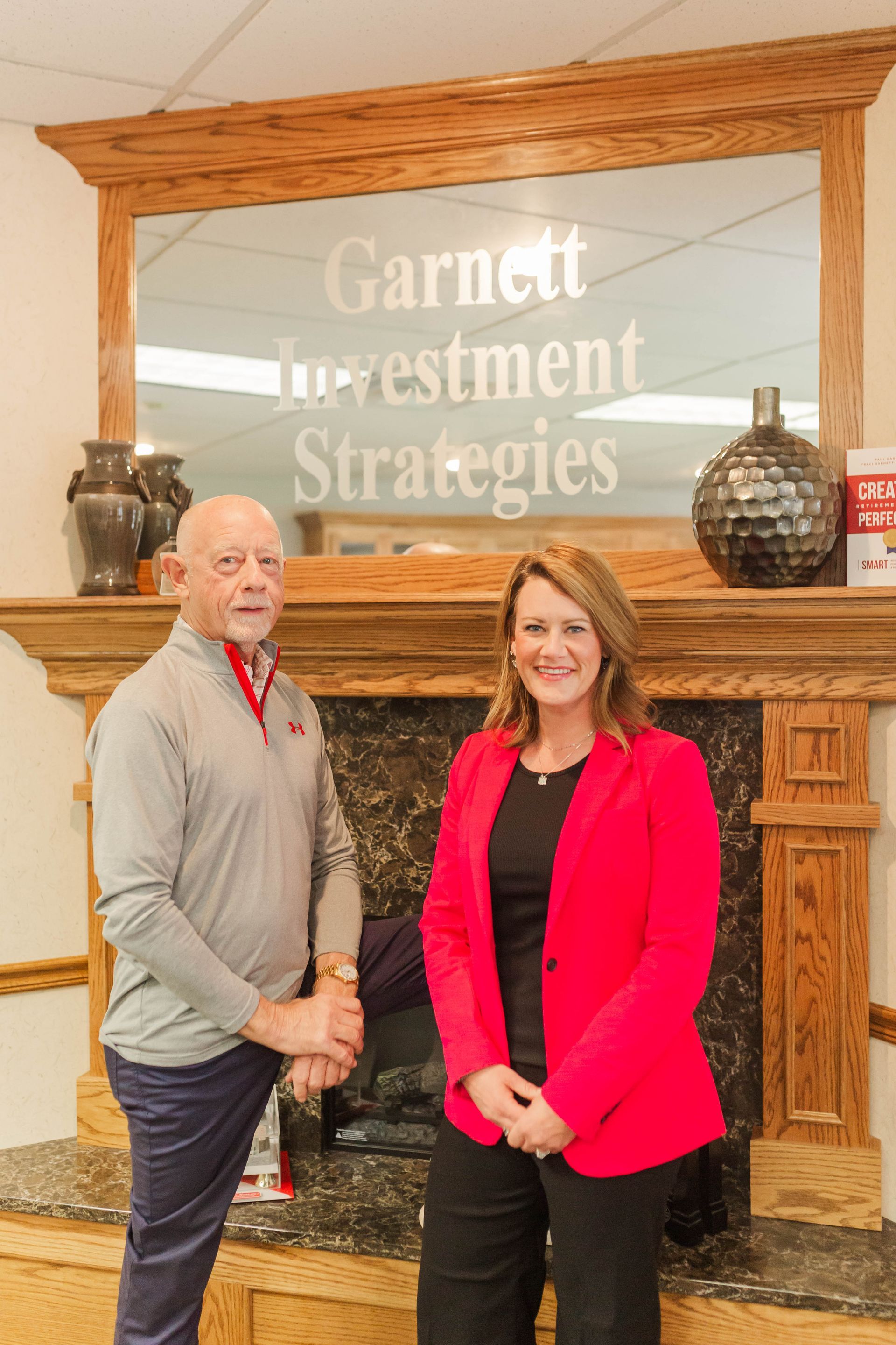 A man and a woman are shaking hands in front of a fireplace.