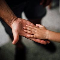 A close up of a person holding a child 's hand