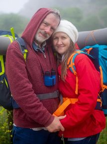 A man and a woman are holding hands while standing next to each other with backpacks.