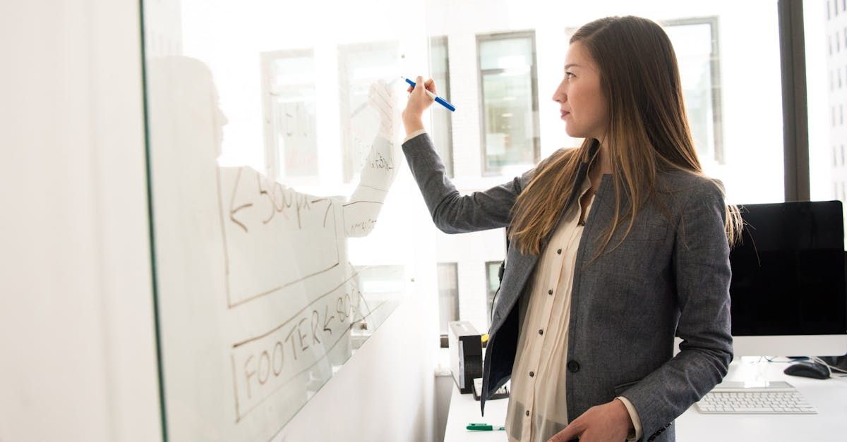 A woman is writing on a whiteboard in an office.