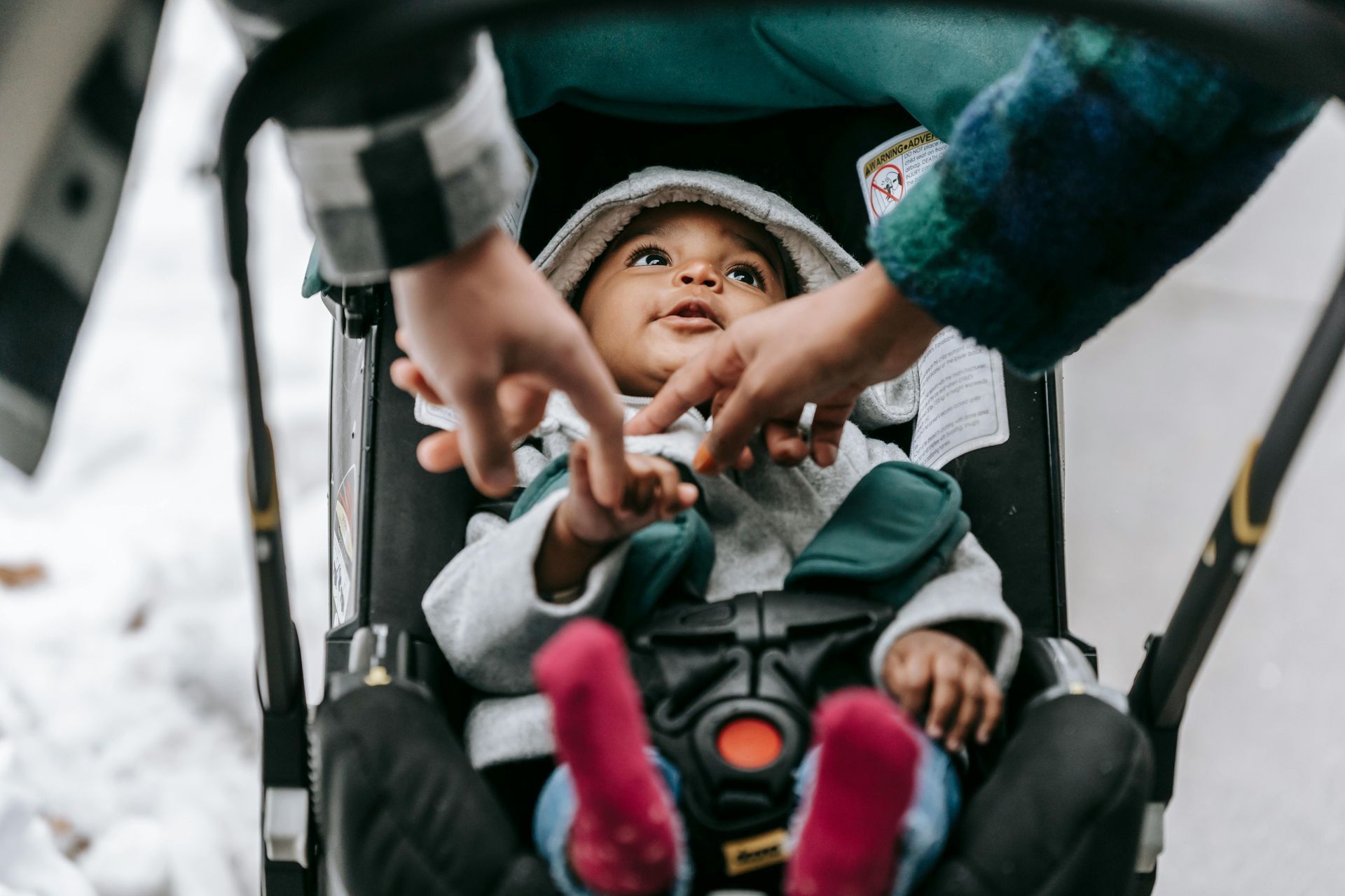 A baby is sitting in a stroller being pushed by a person.