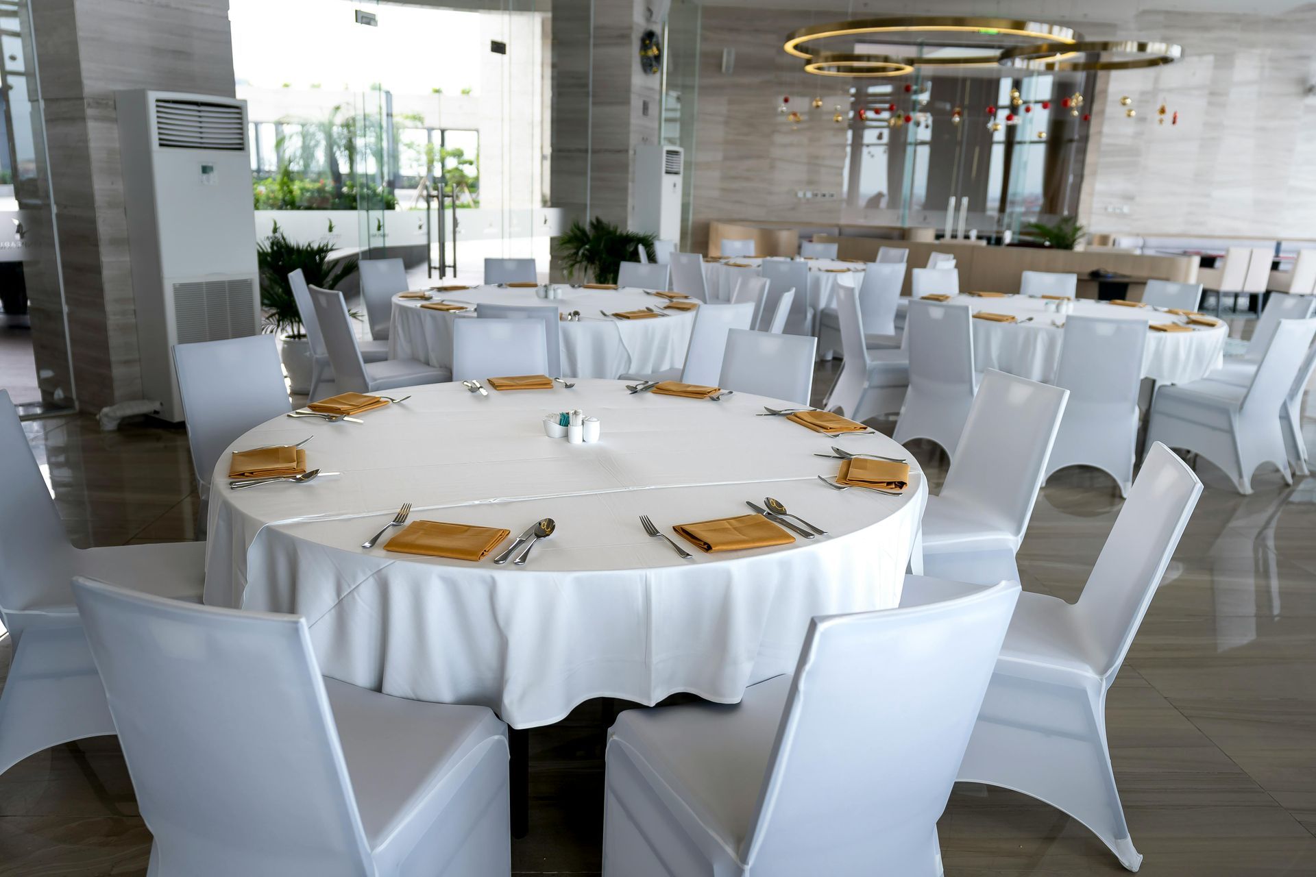 A large room with tables and chairs set up for a wedding reception.