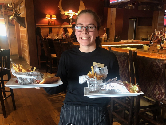server smiling holding trays of food