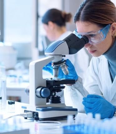 Scientist in blue gloves using a microscope in a bright laboratory