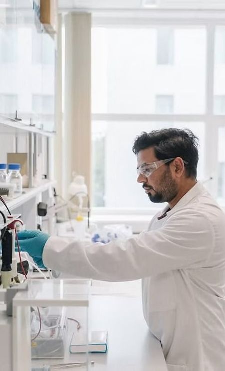 Scientist in a white lab coat working with lab equipment in a bright laboratory.