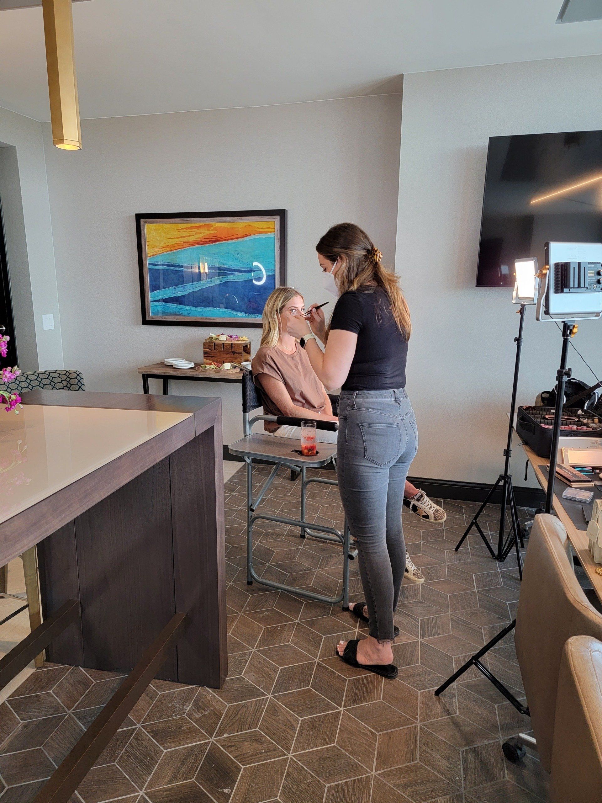 A woman is applying makeup to another woman in a room.
