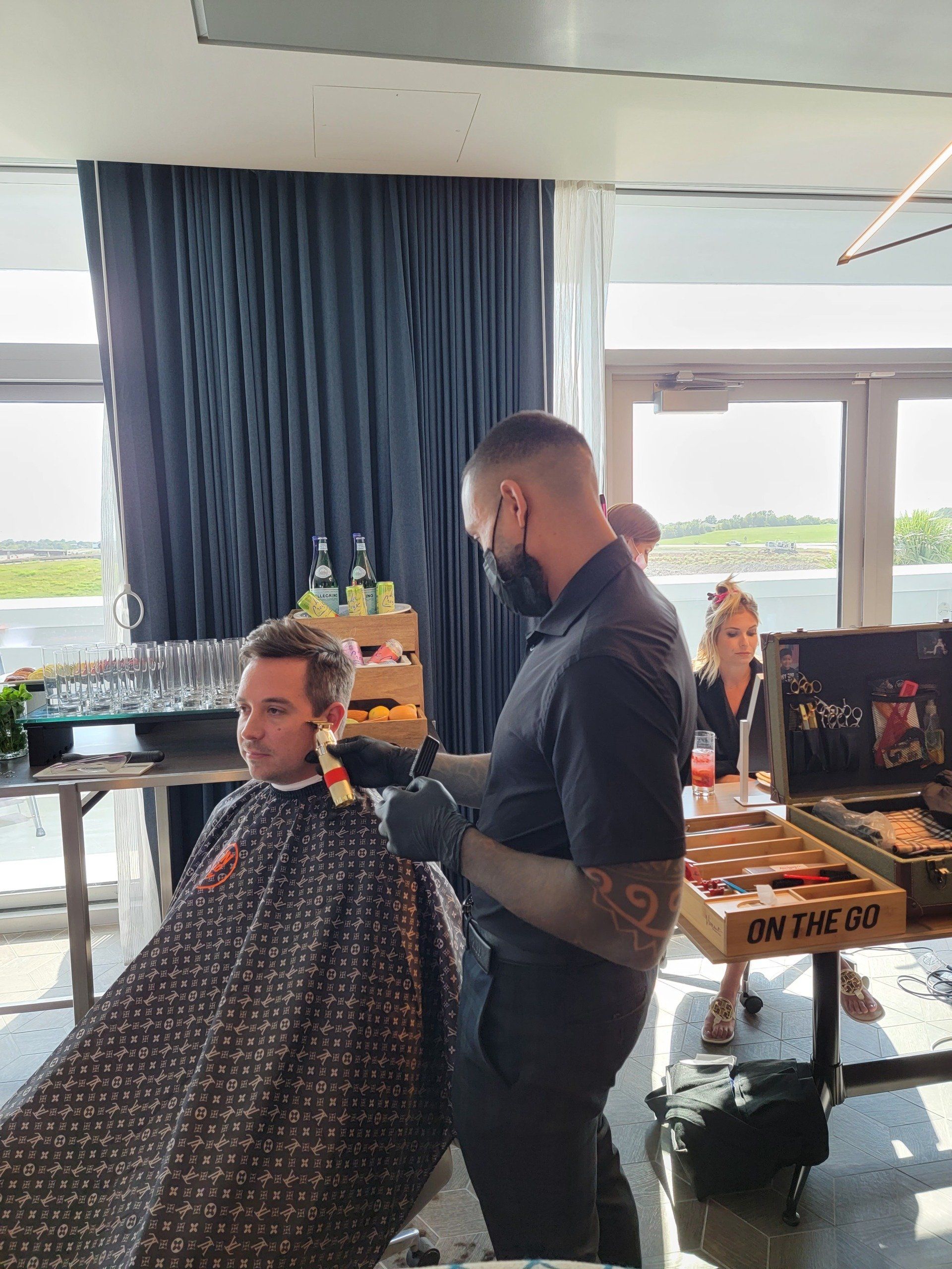 A man is getting his hair cut by a barber in a room.