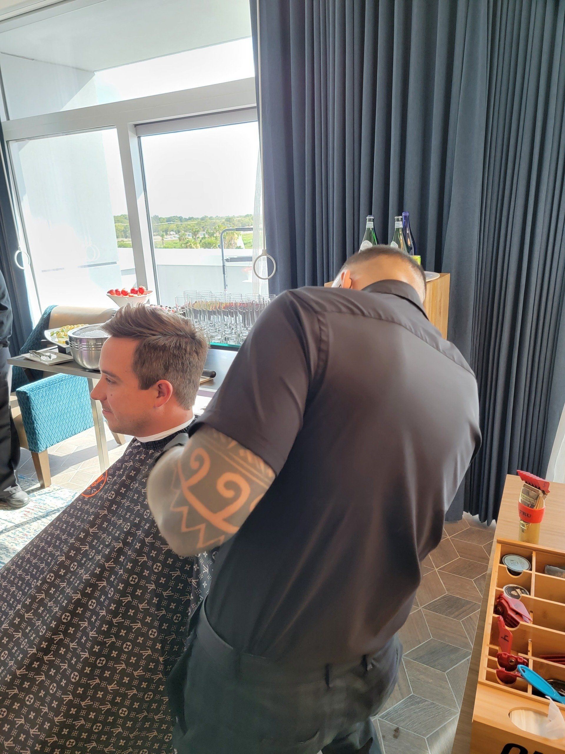 A man is getting his hair cut by a barber in a room.