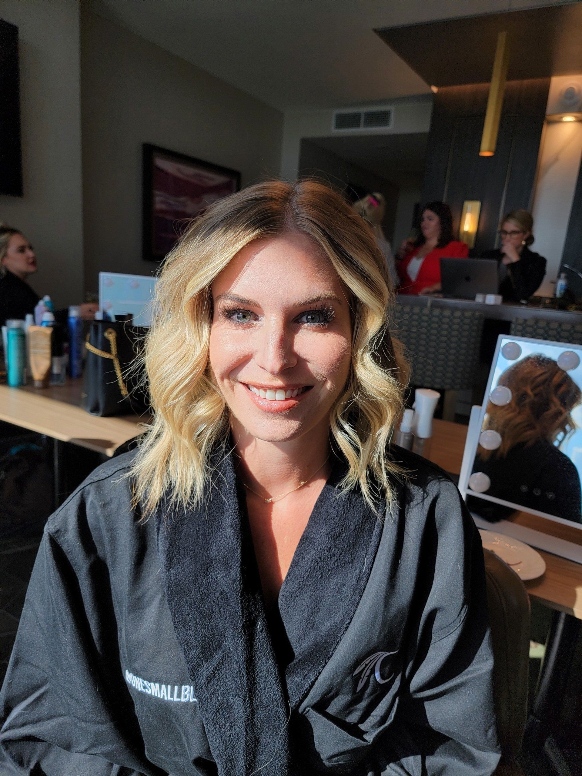 A woman in a black robe is smiling in a room.