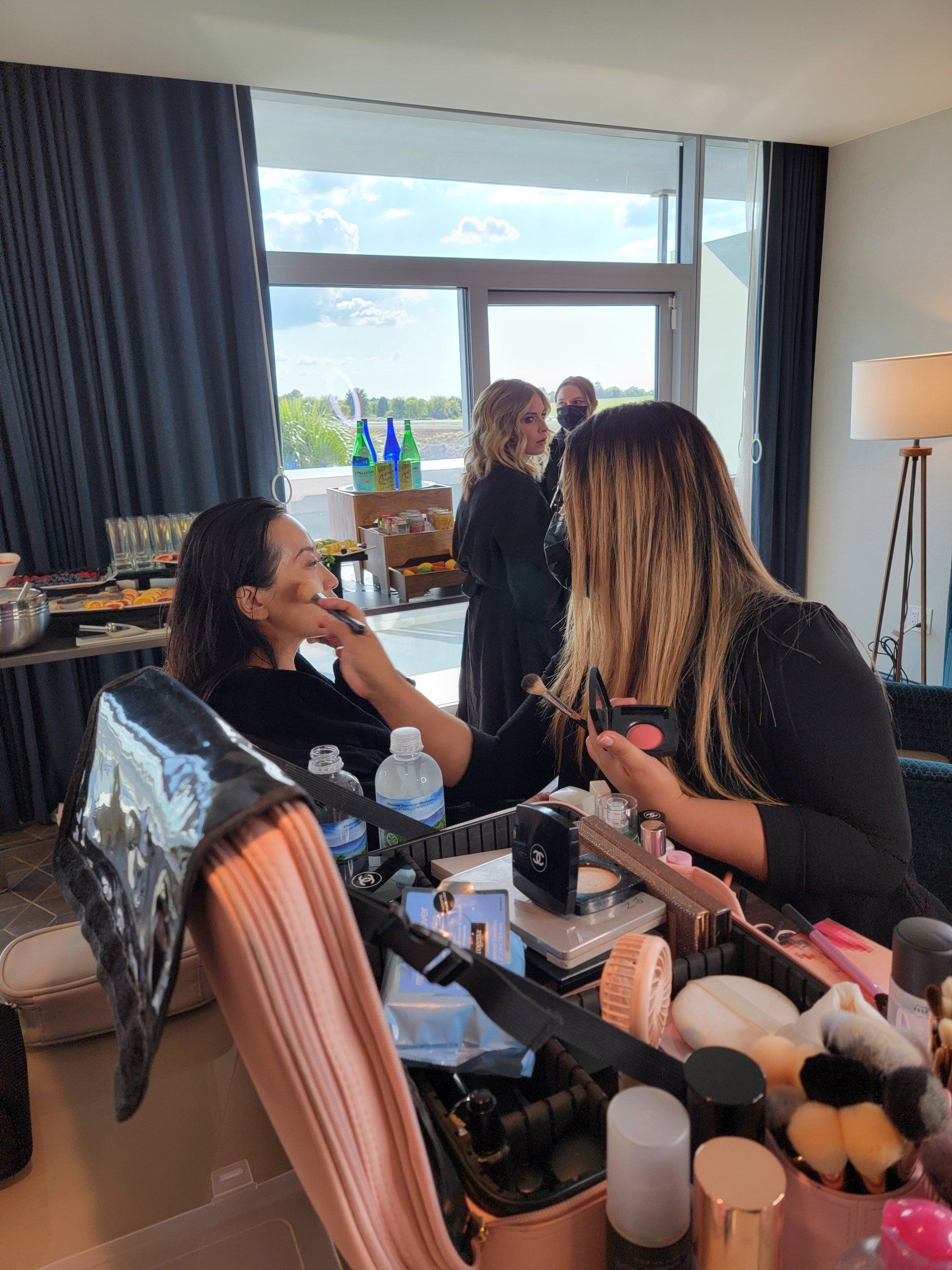 Two women are applying makeup to each other in a room.