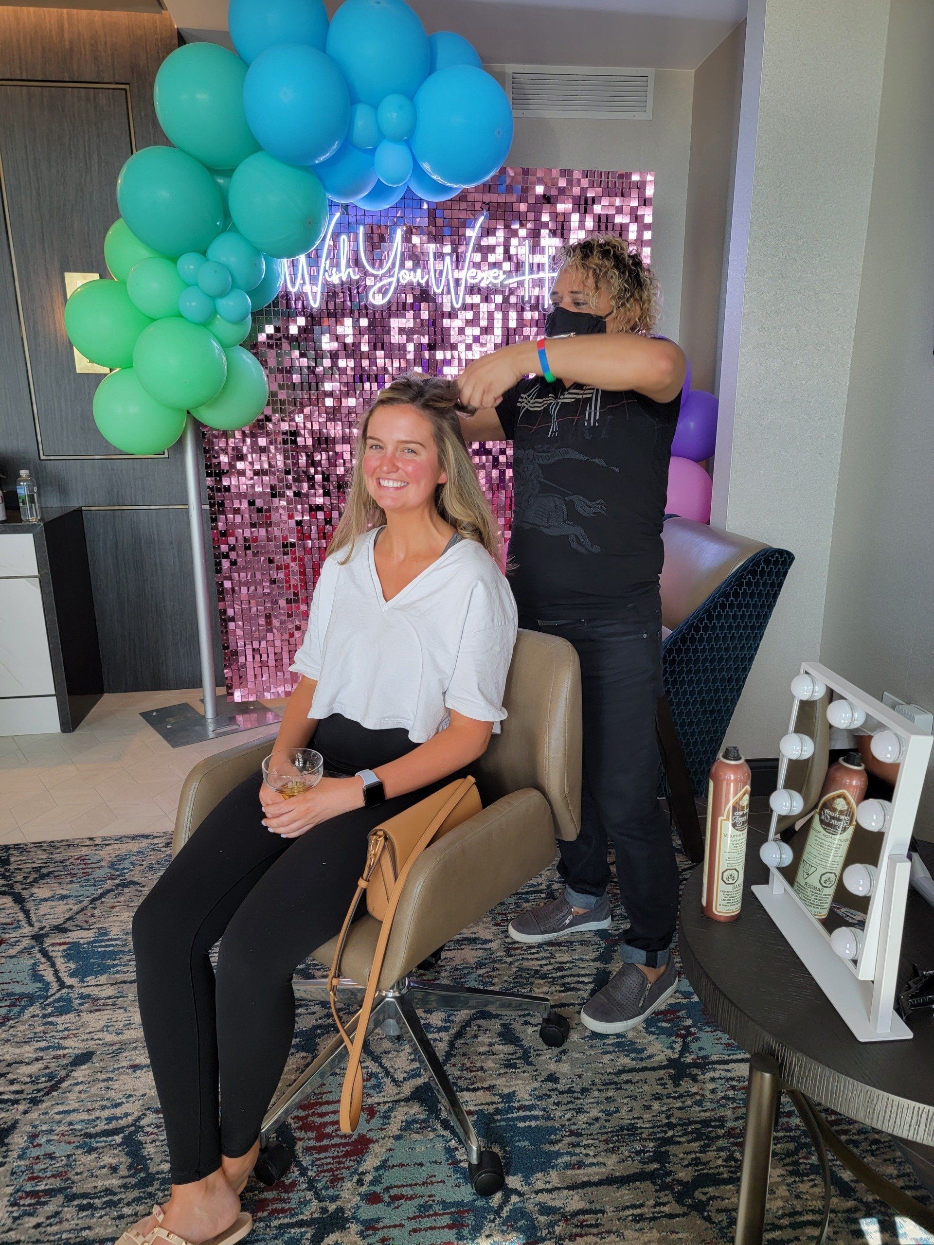 A woman is sitting in a chair getting her hair done by a hairdresser.