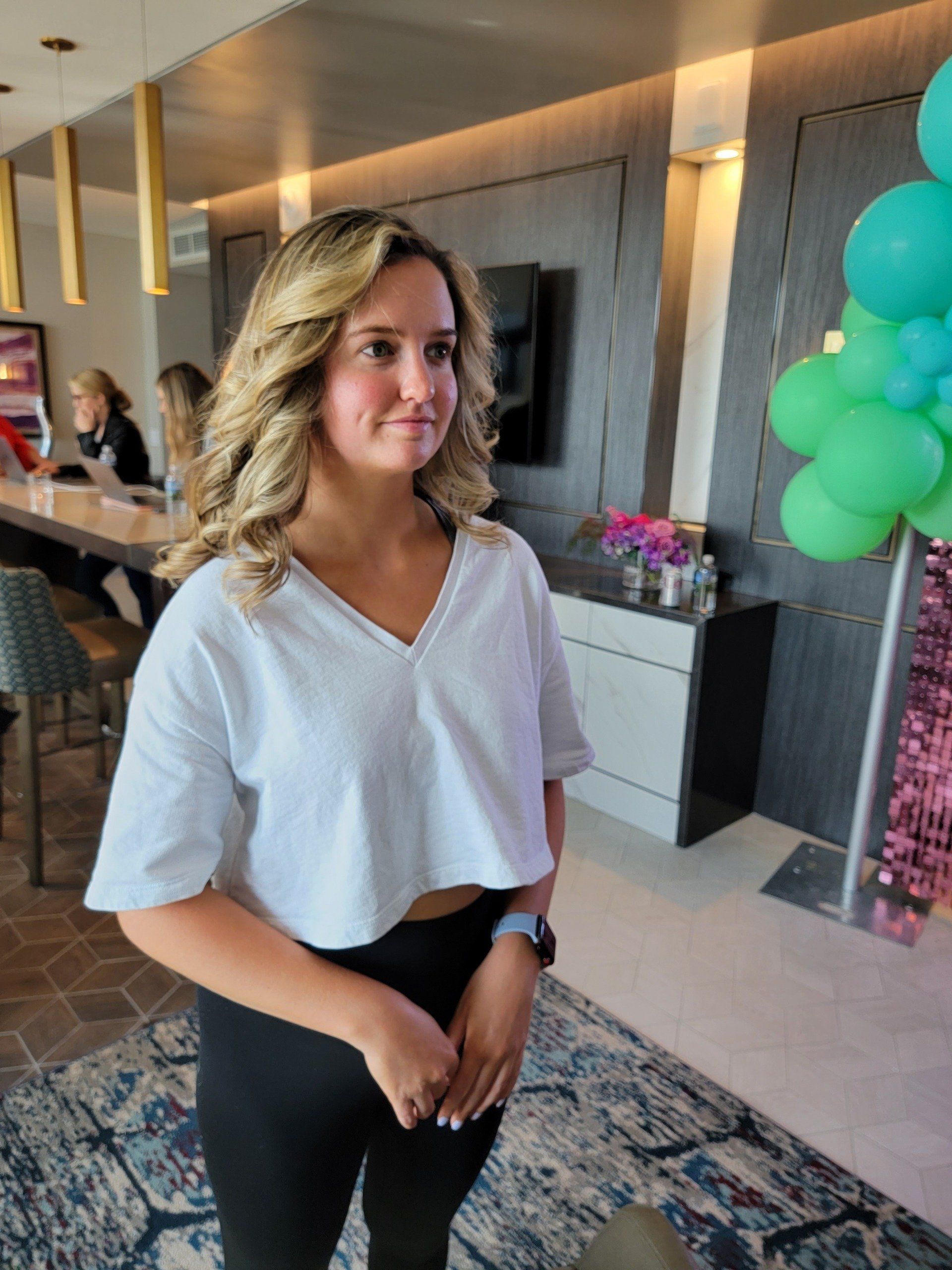 A woman in a white crop top is standing in a room with balloons.