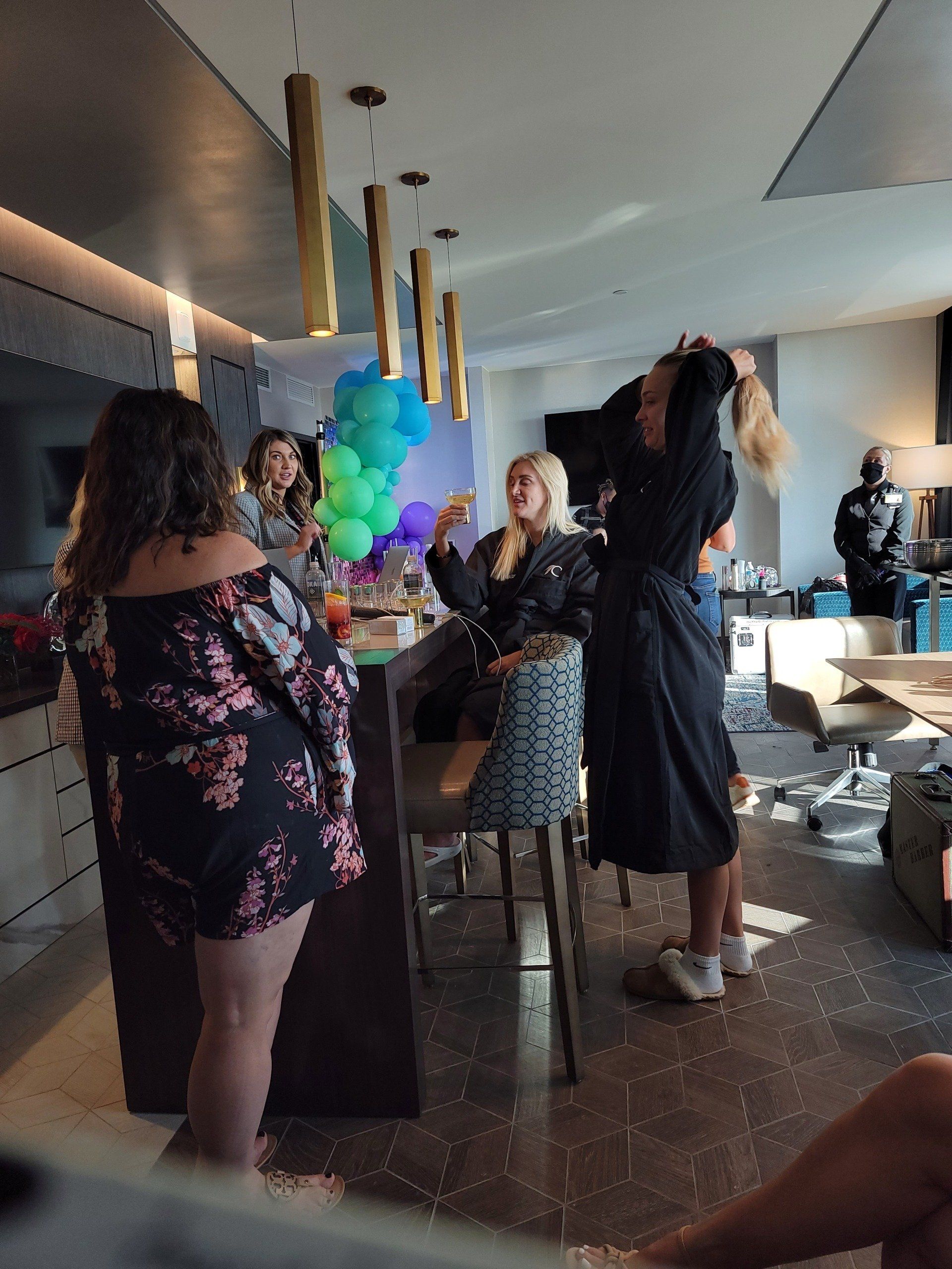 A group of women are standing in a room with balloons hanging from the ceiling.